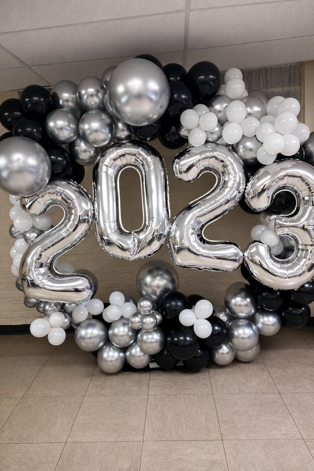 Black, silver and white New Year’s Eve balloon backdrop featuring large “2023” foil numbers.
