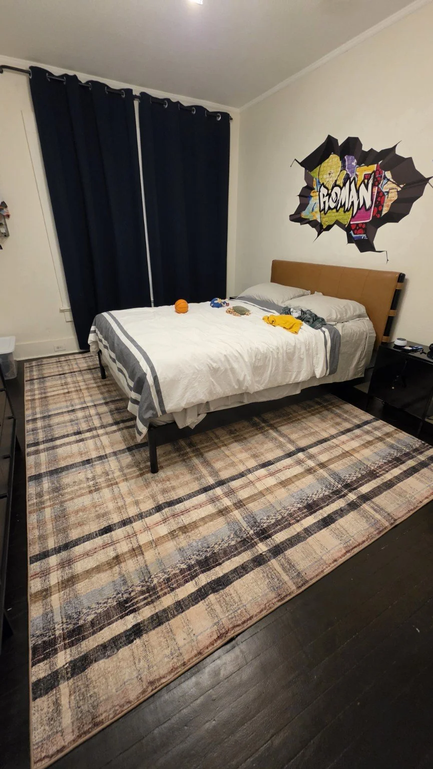 Boy’s bedroom refresh in progress with a cognac queen bed, black nightstand and plaid area rug