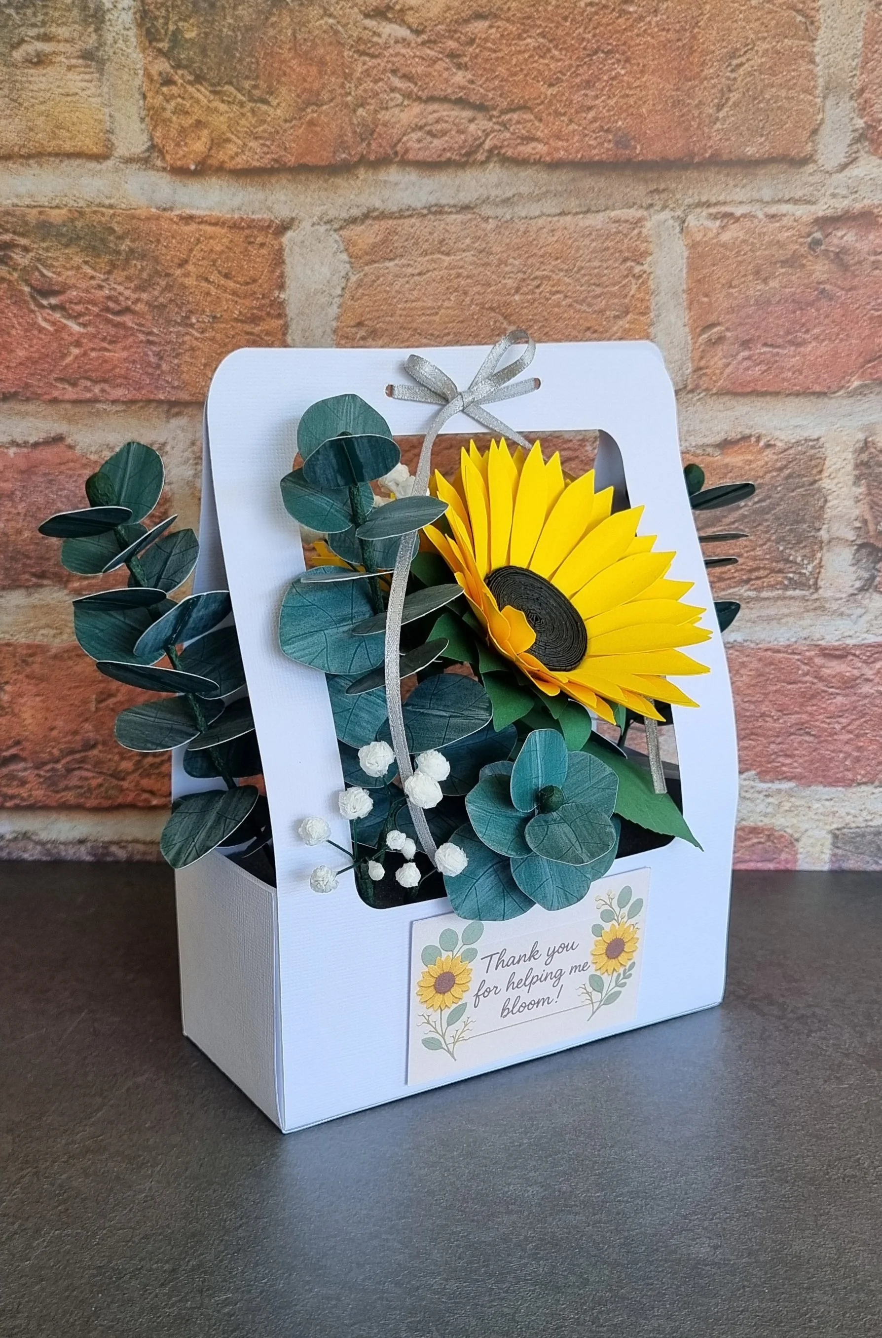 Close-up of the “Thank you for helping me bloom!” plaque attached to the flower box, with the sunflower and greenery softly blurred in the background..jpg