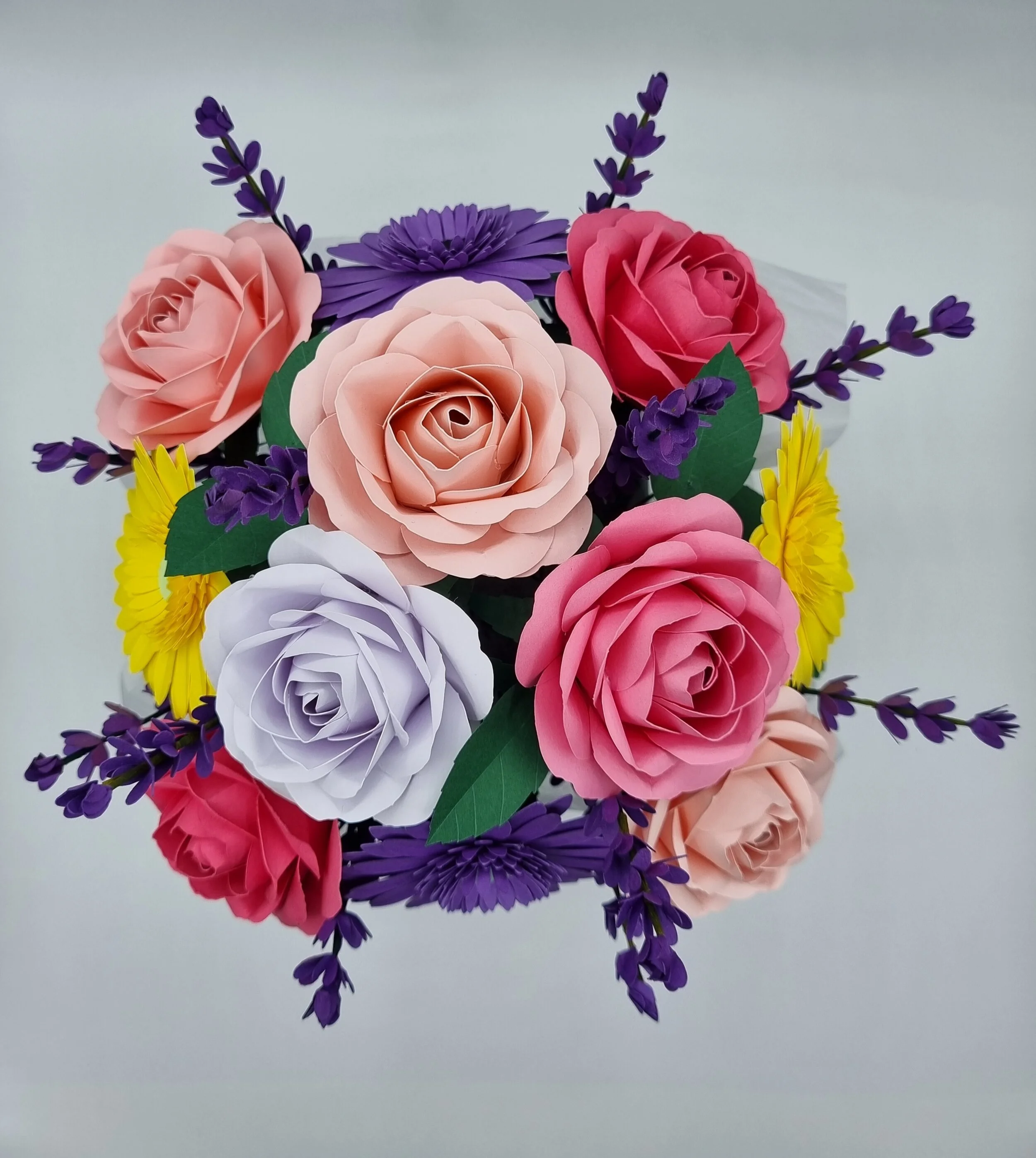 Paper flower bouquet featuring pink, white, purple, and yellow flowers with green leaves.