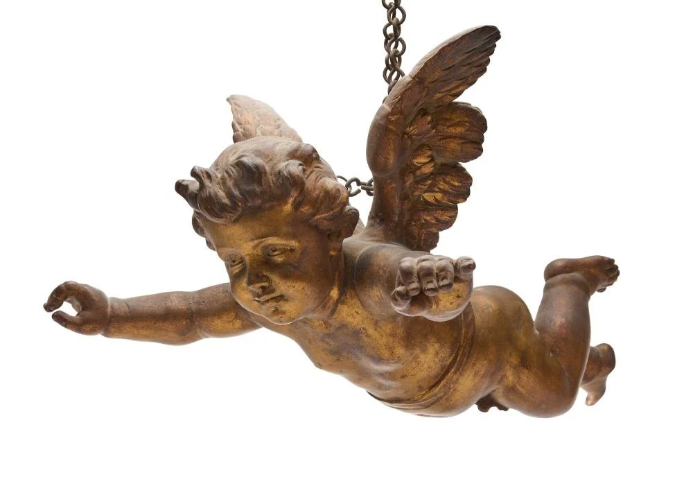 Gilded cherub hanging from the ceiling with a chain
