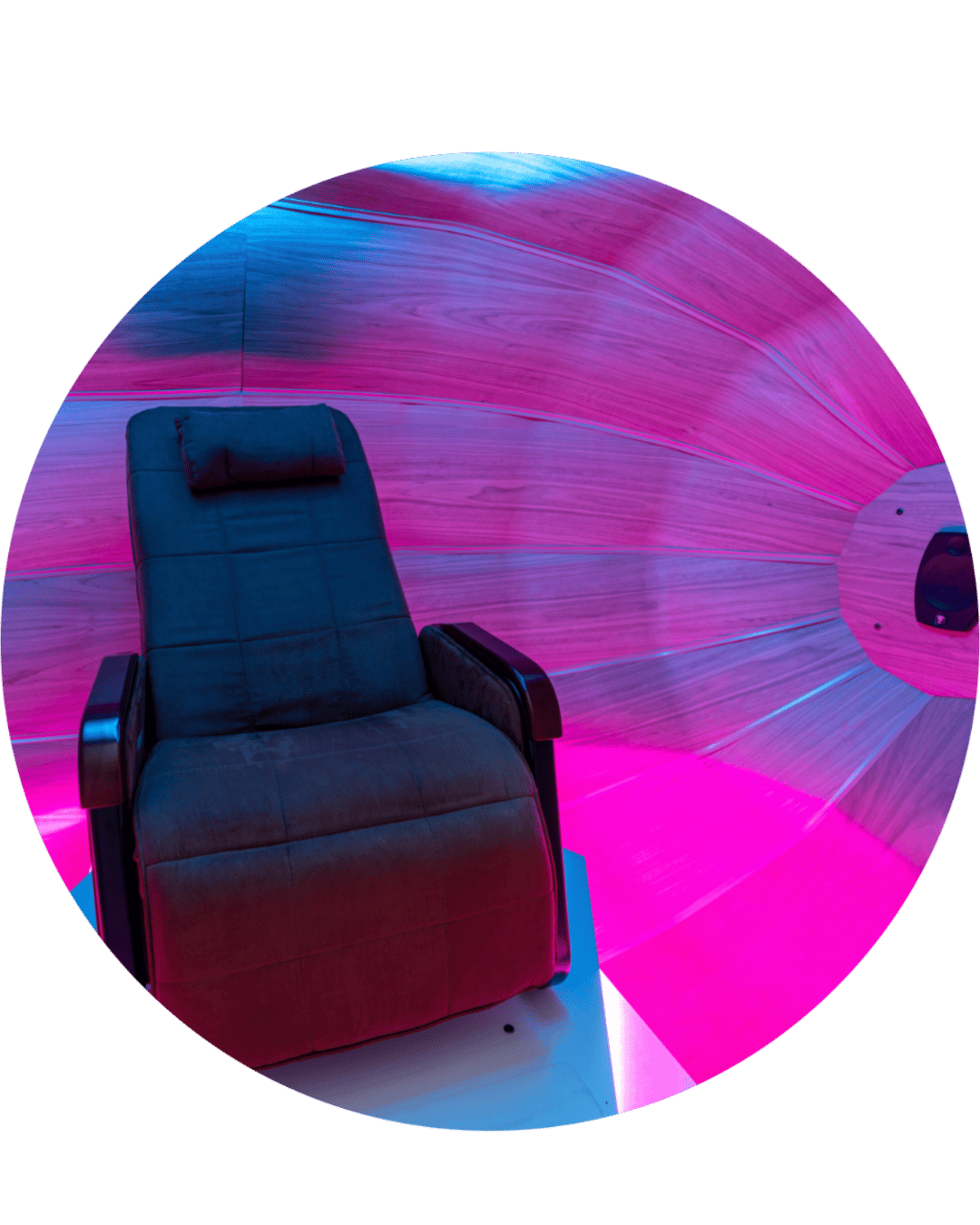A black massage chair in a room with pink, purple, and blue LED lighting, and a wood-paneled curved wall.