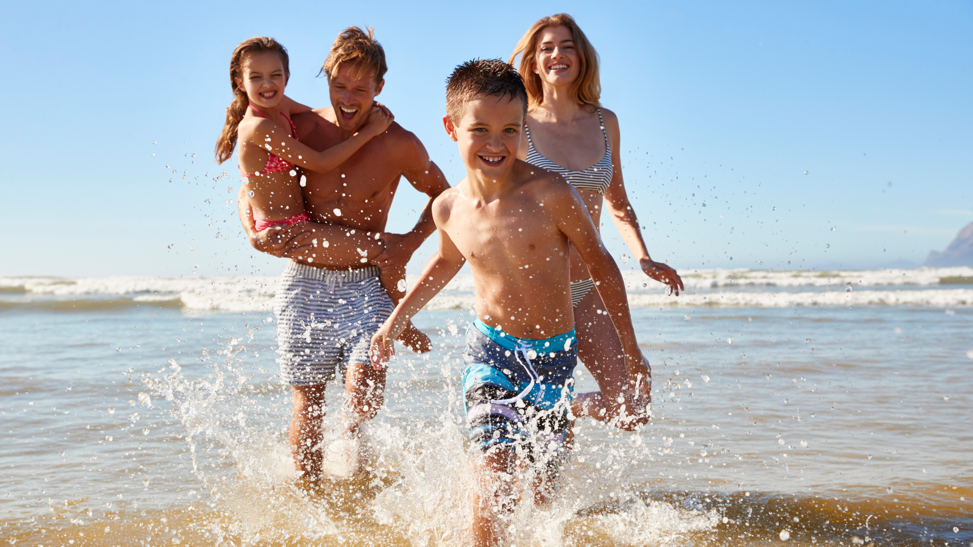 A family of four playing and running around the beach in Carpinteria, California.