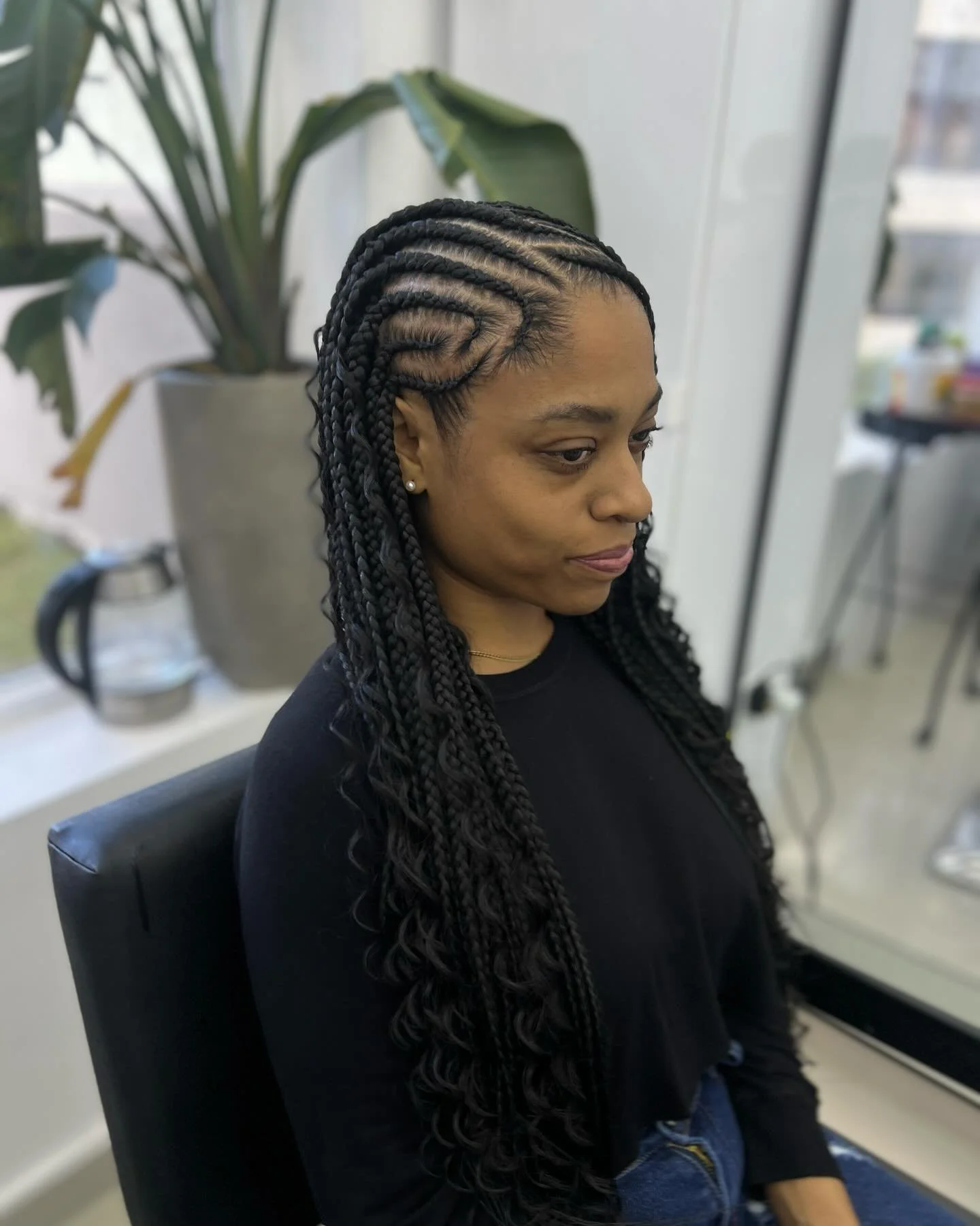 A woman with long, braided hair sitting in a salon chair.