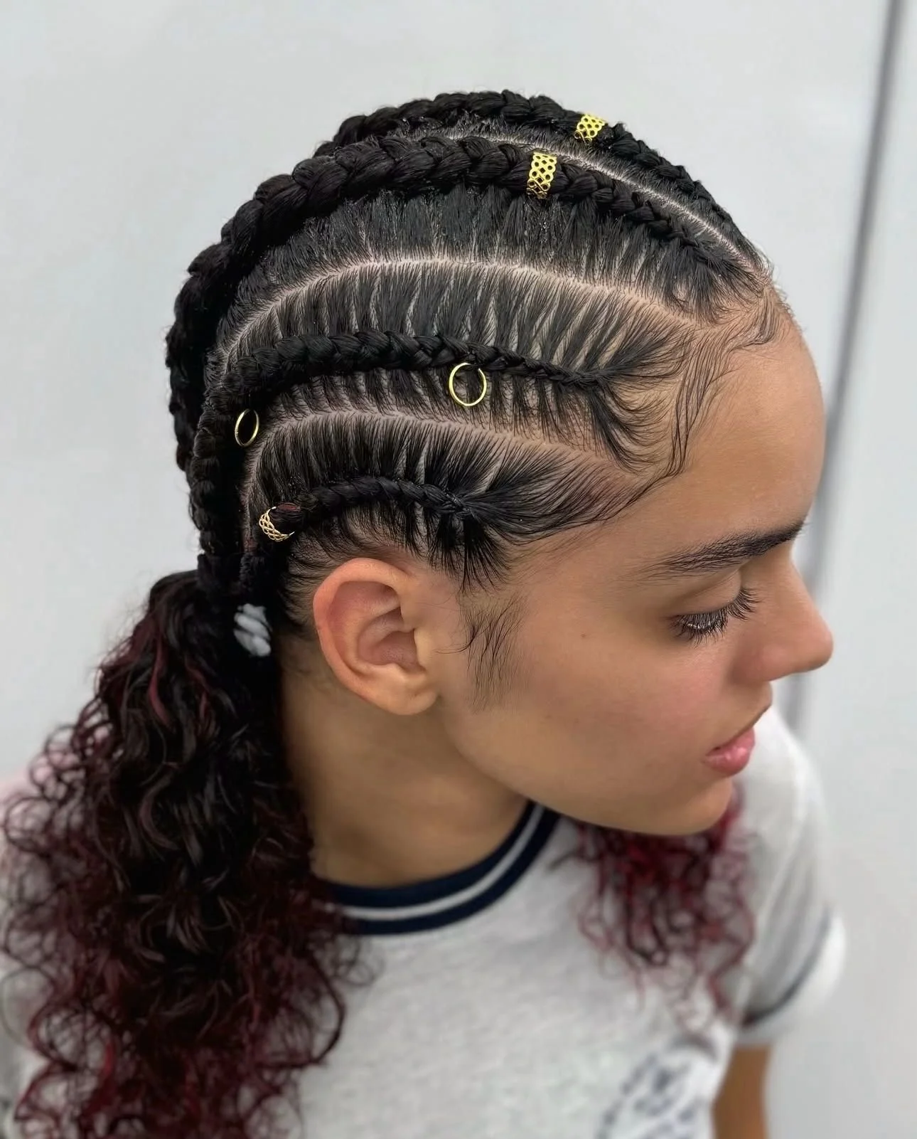 Close-up of a woman with intricately braided hair decorated with gold and metallic hair accessories.