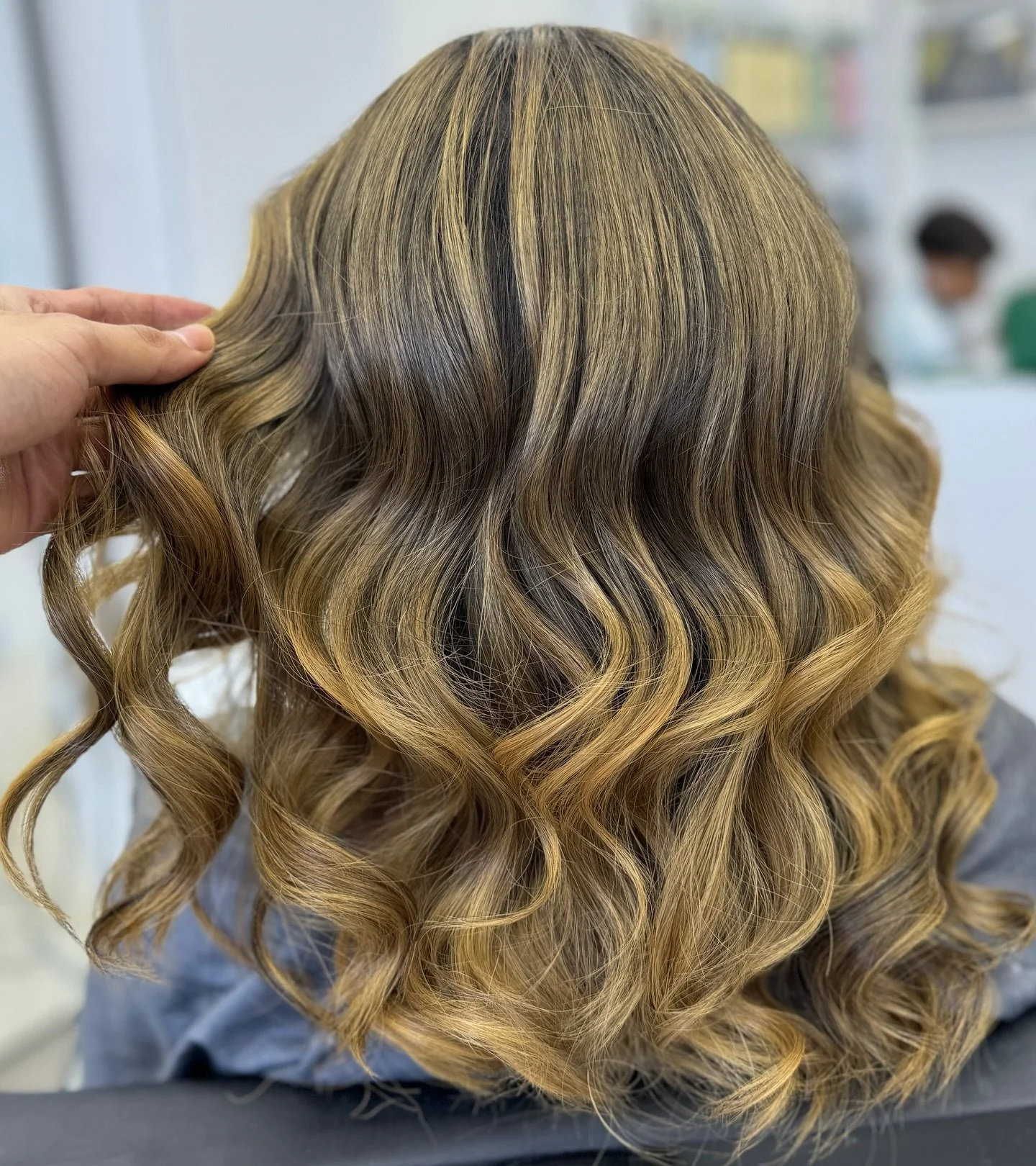 Blonde hair with dark roots styled in loose curls.