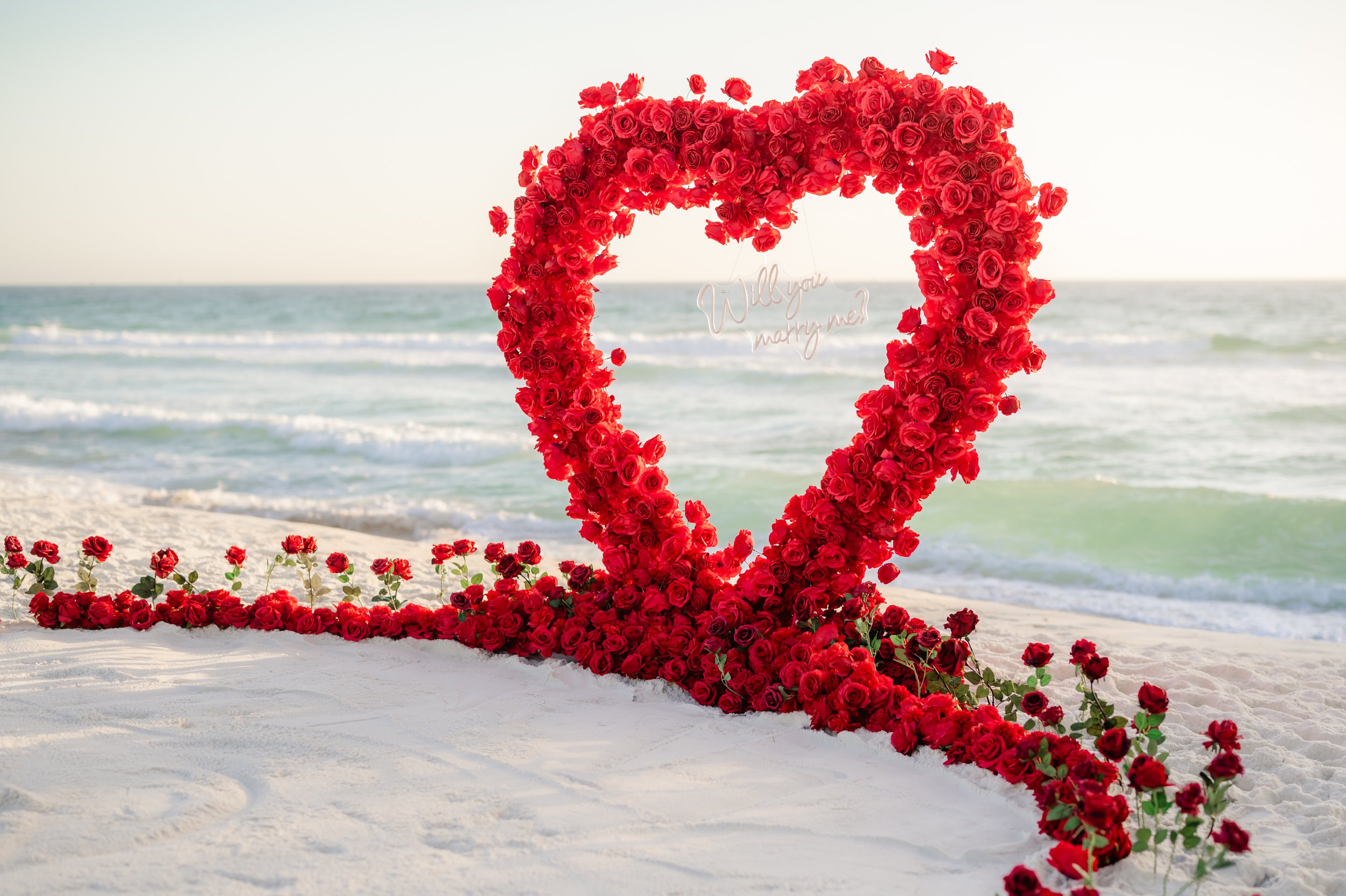 luxury red rose heart arch set up on the beach for proposa set up by coastal blooml to be photographed by Panama City beach photographers