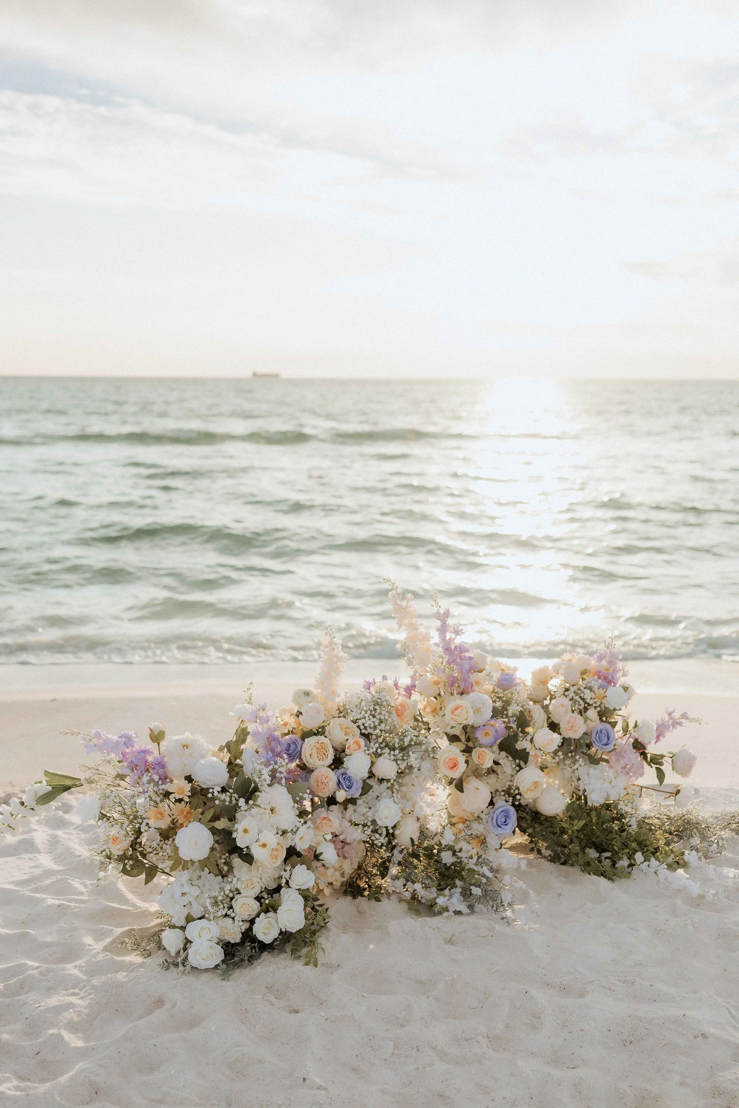 luxury Floral wedding arch on the beach during sunset  at St andrews state park in Panama City beach Florida with ocean waves in the background.