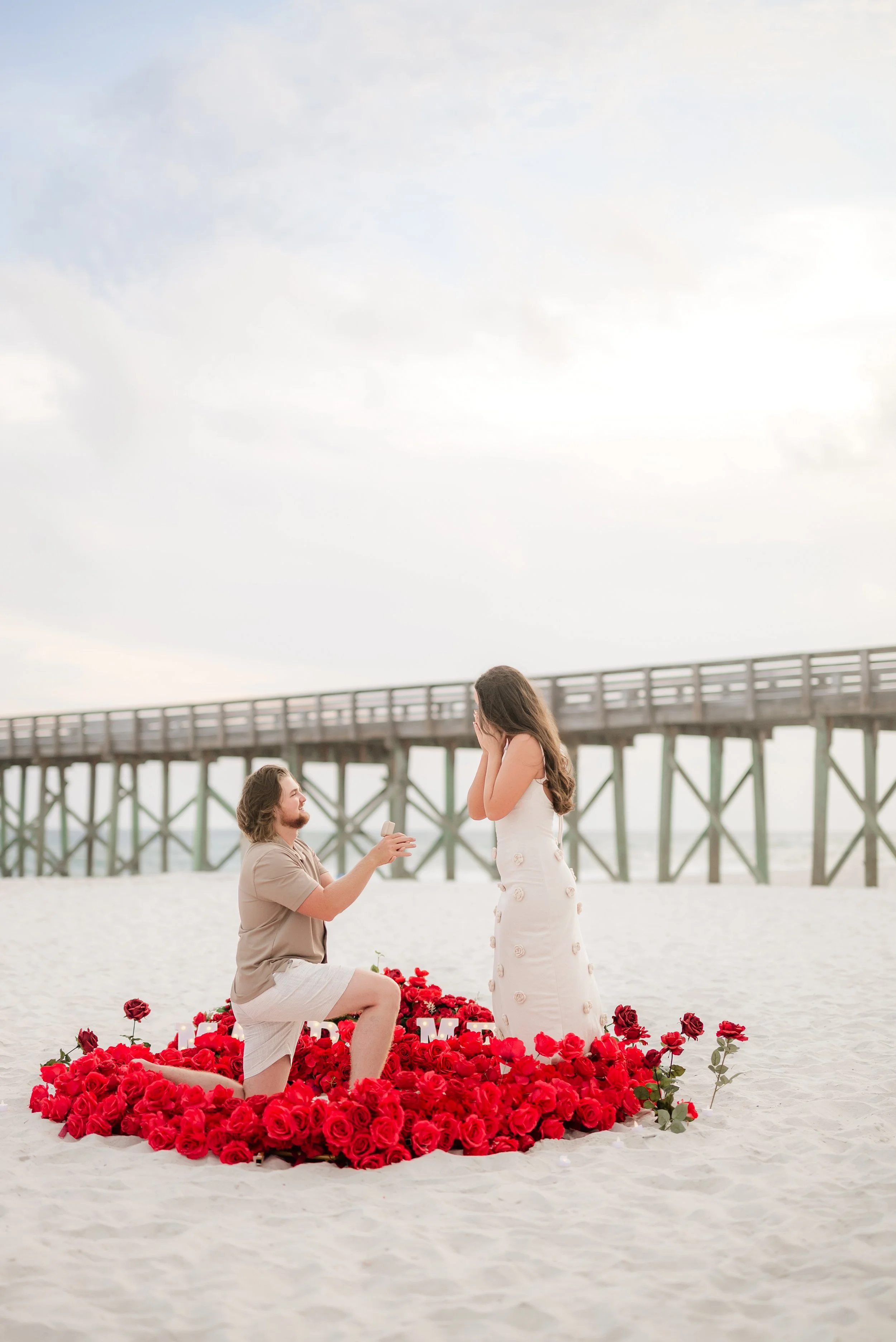 man proposing at st andrews state park beach in Panama City beach with red rose set up in a heart from coastal bloom