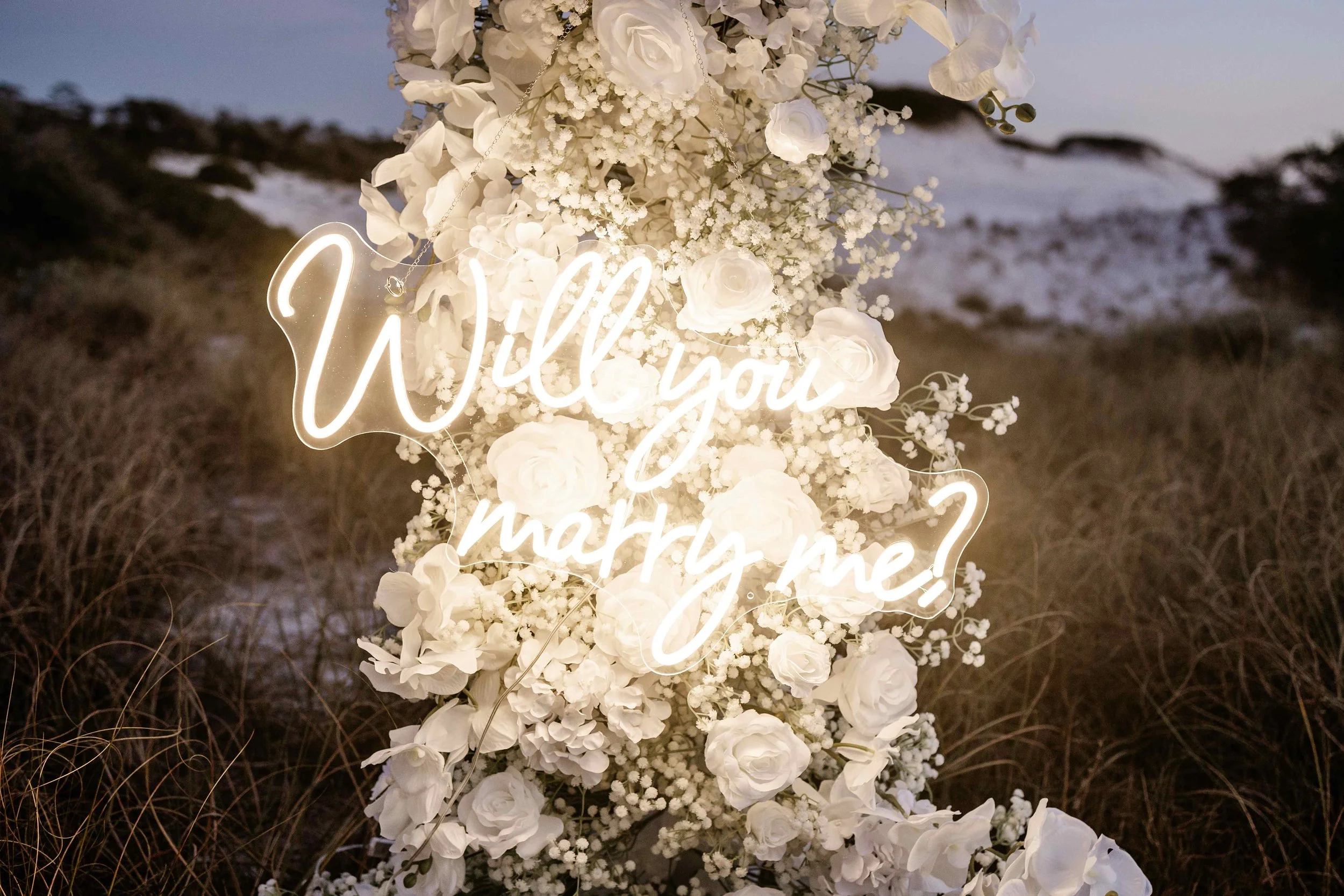 Panama City Beach Proposal with red rose set up from coastal bloom, photos by Panama City beach photographers team. neon will you marry me sign!