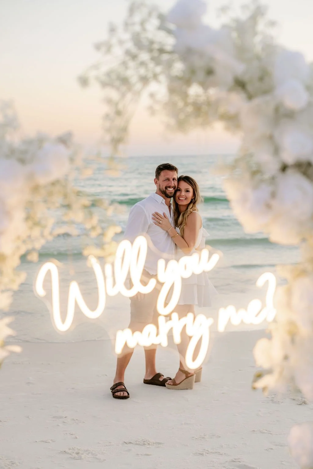 Panama City Beach Proposal with white rose set up and marry me sign from coastal bloom, photos by Panama City beach photographers team 