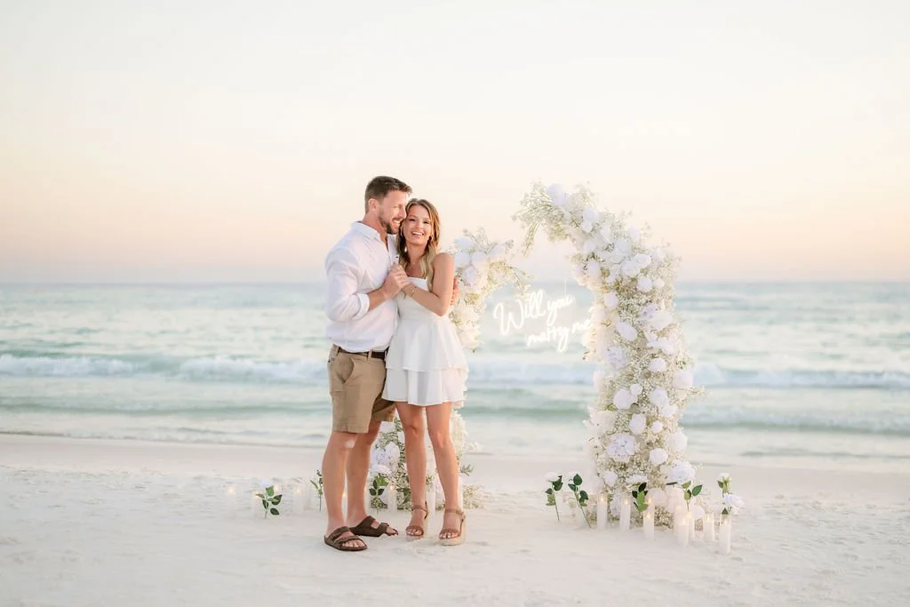 Panama City Beach Proposal with white rose set up and marry me sign from coastal bloom, photos by Panama City beach photographers team 