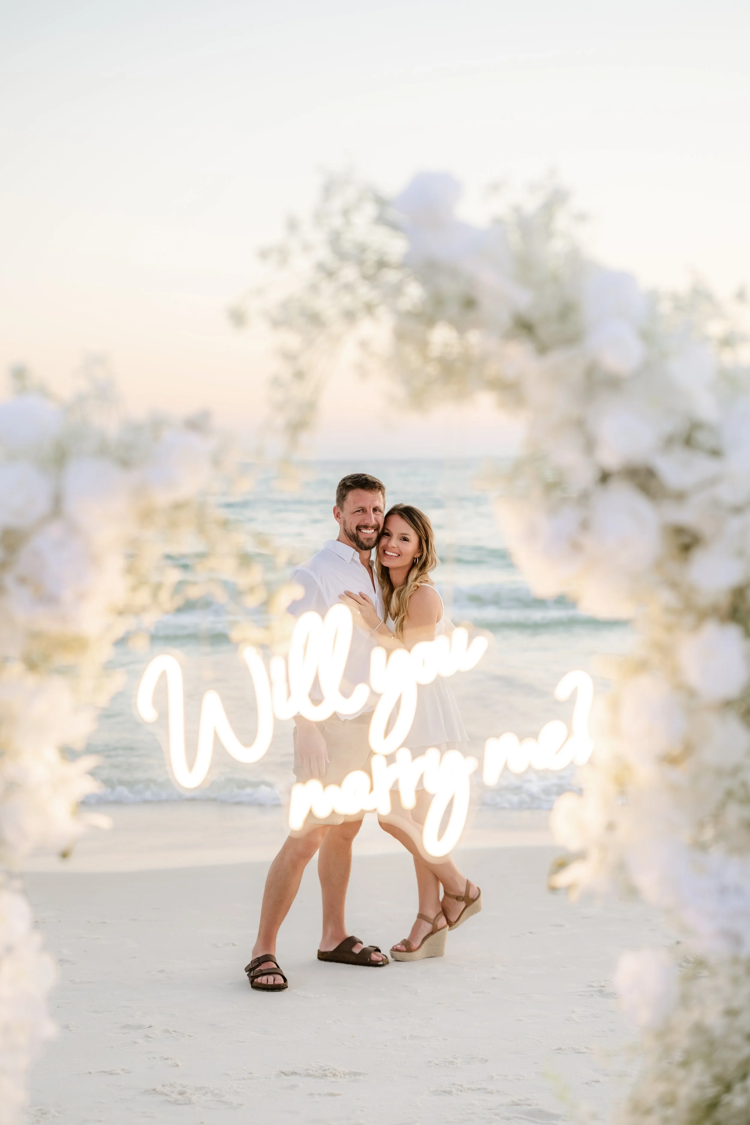 Panama City Beach Proposal with white rose set up and marry me sign from coastal bloom, photos by Panama City beach photographers team 