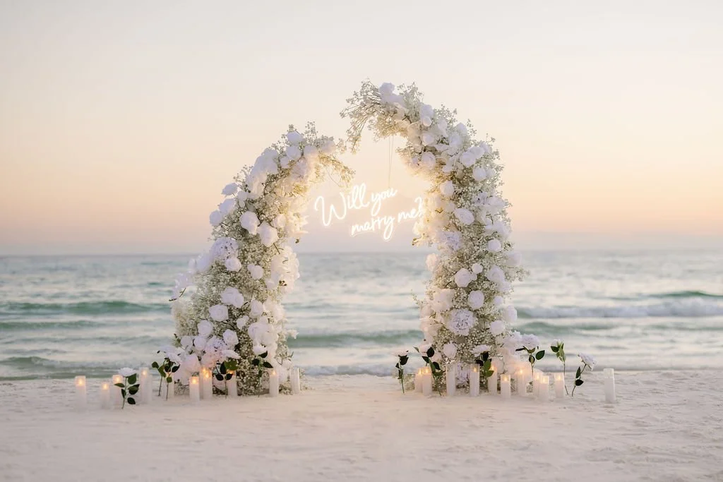 Panama City Beach Proposal with white rose set up and marry me sign from coastal bloom, photos by Panama City beach photographers team 