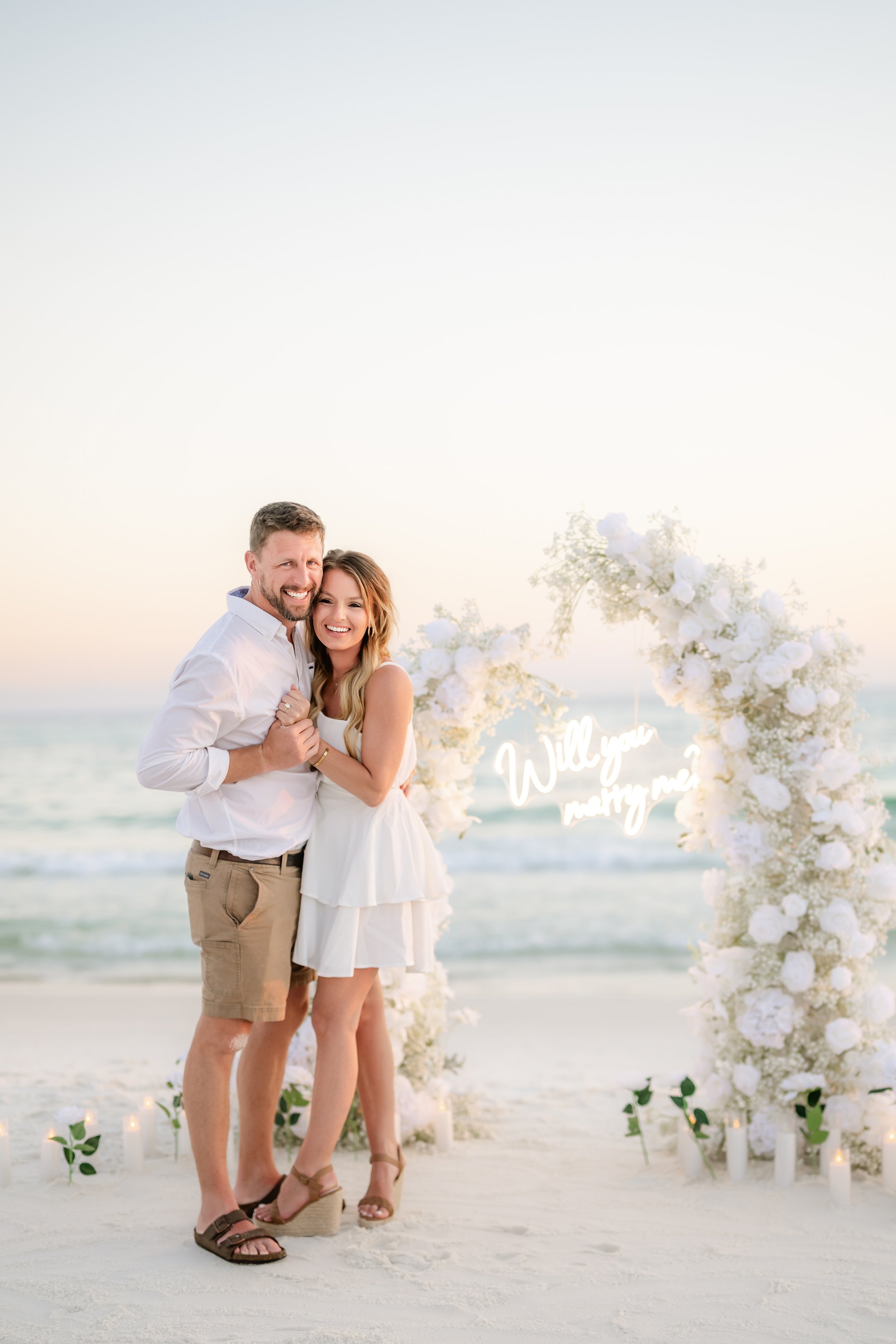Panama City Beach Proposal with white rose set up and marry me sign from coastal bloom, photos by Panama City beach photographers team 
