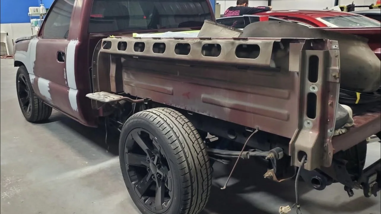 Partially disassembled pickup truck with exposed rear frame and missing bed.