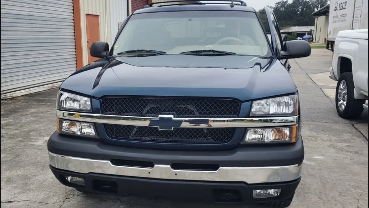 Front view of a blue Chevrolet SUV parked outside, showing grille, headlights, and chrome accents.