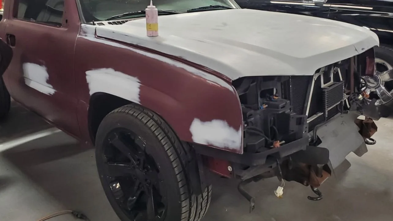 Partially disassembled truck being repaired and prepared for painting in a garage.