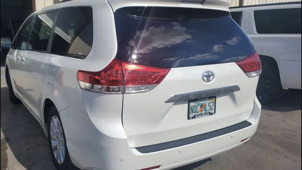White Toyota Sienna minivan parked outdoors with a Florida license plate.