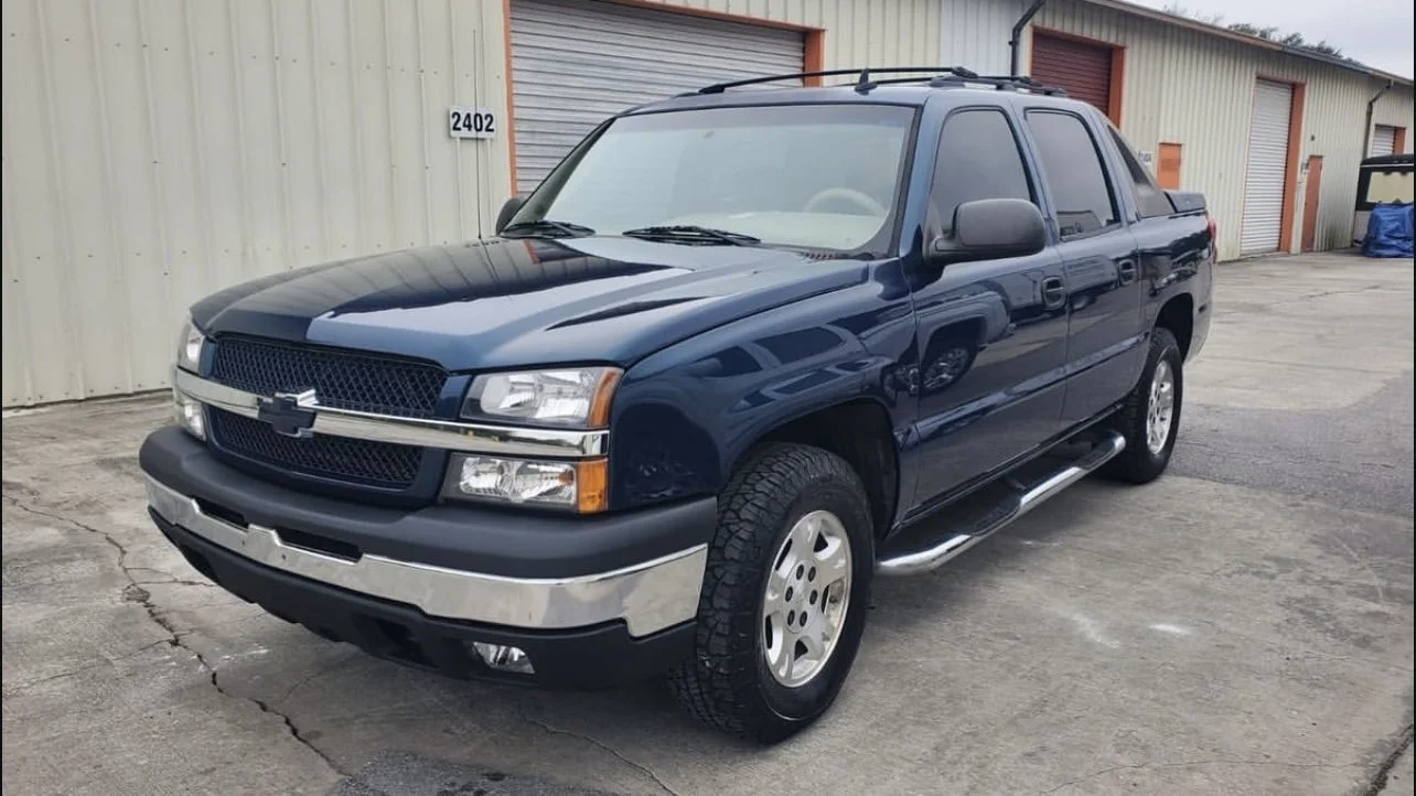 Blue Chevrolet Avalanche parked near storage units.
