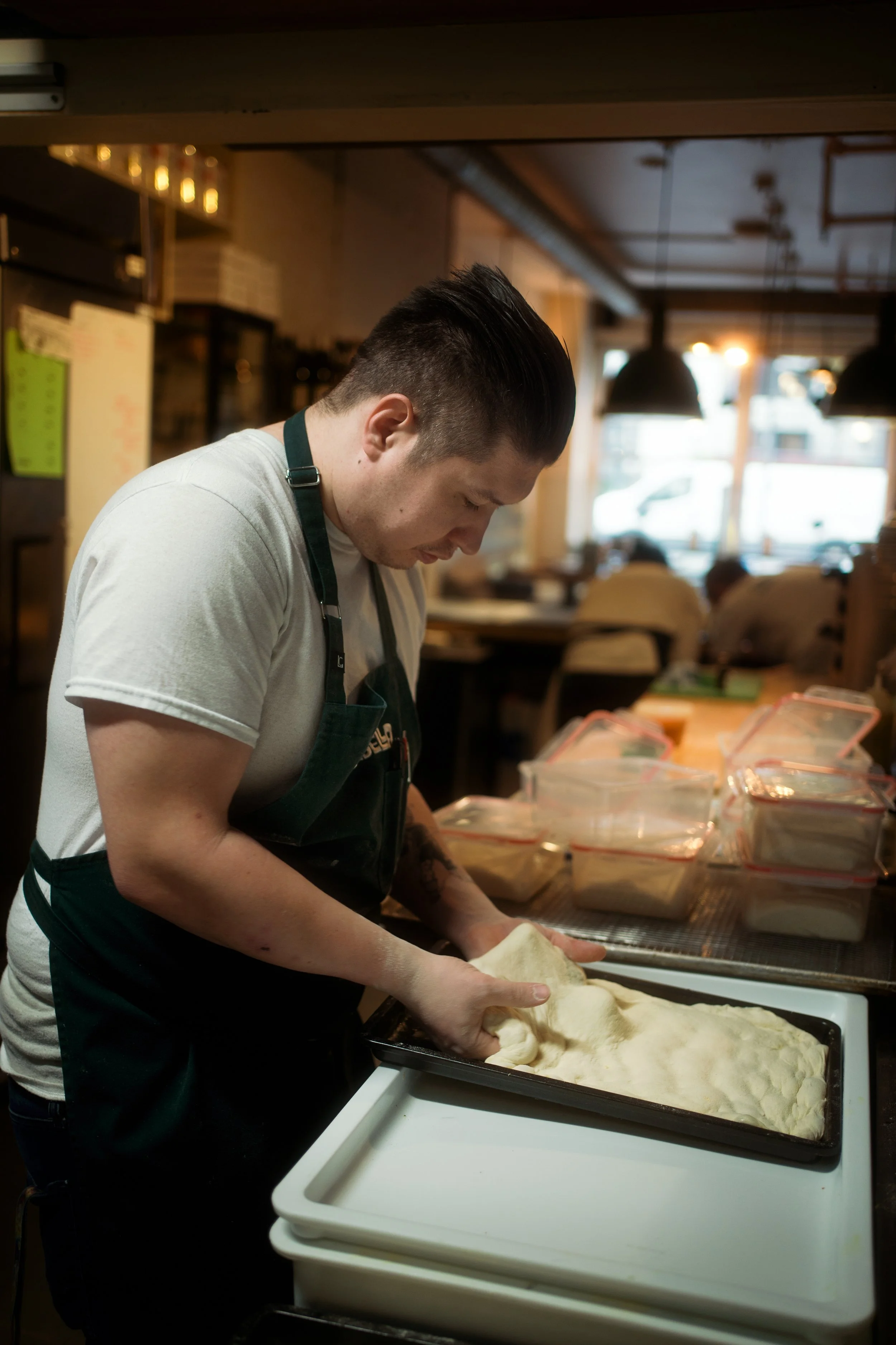 A man working with dough in a kitchen or bakery setting.