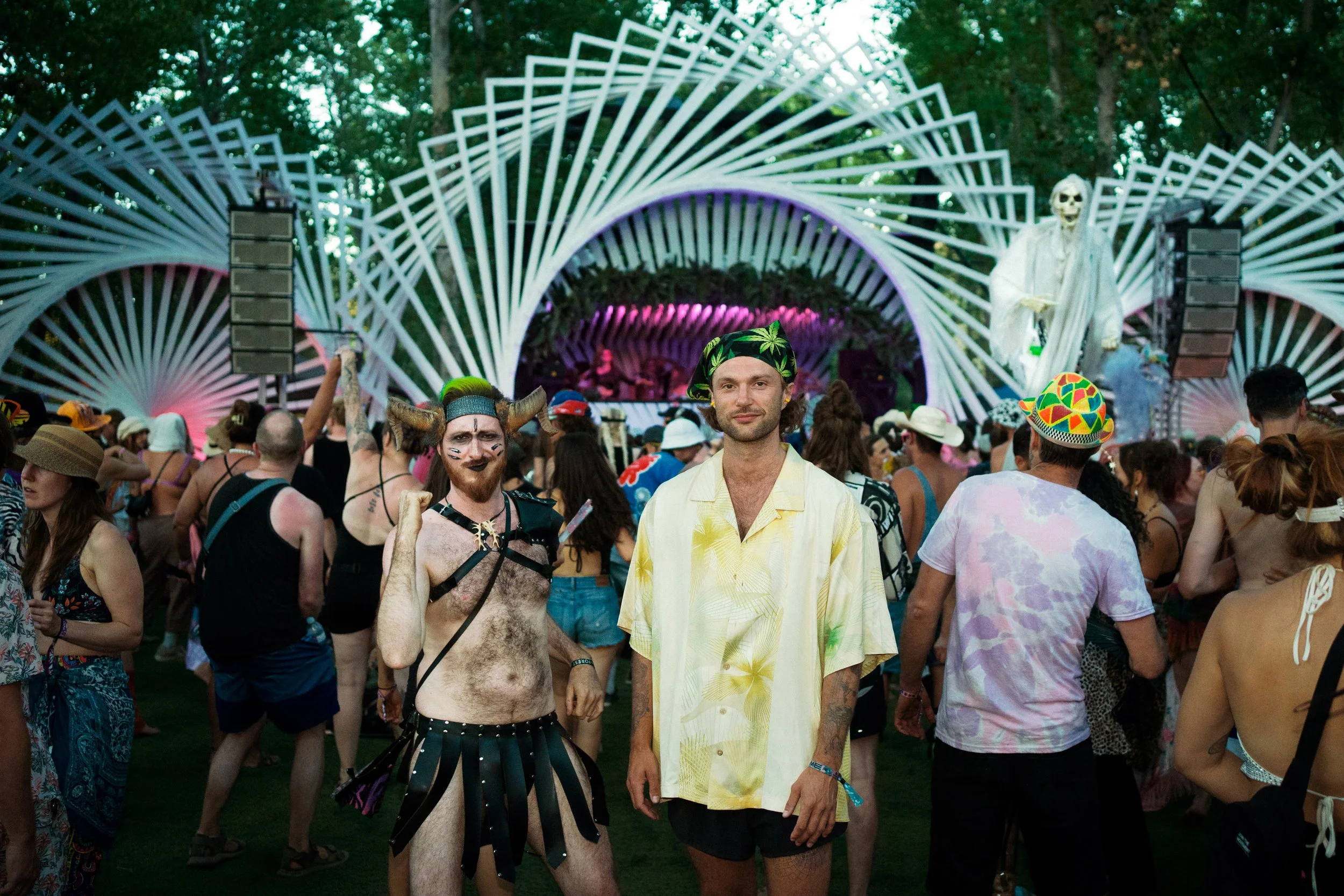 Crowd of festival-goers at an outdoor music event, with two men in the front dressed in costumes and colorful outfits, ;10 Things I Learned Rawdogging a 4-Day Rave Without Booze or Drugs for Vice Magazine and Vice Media, and Bass Coast Music Festival