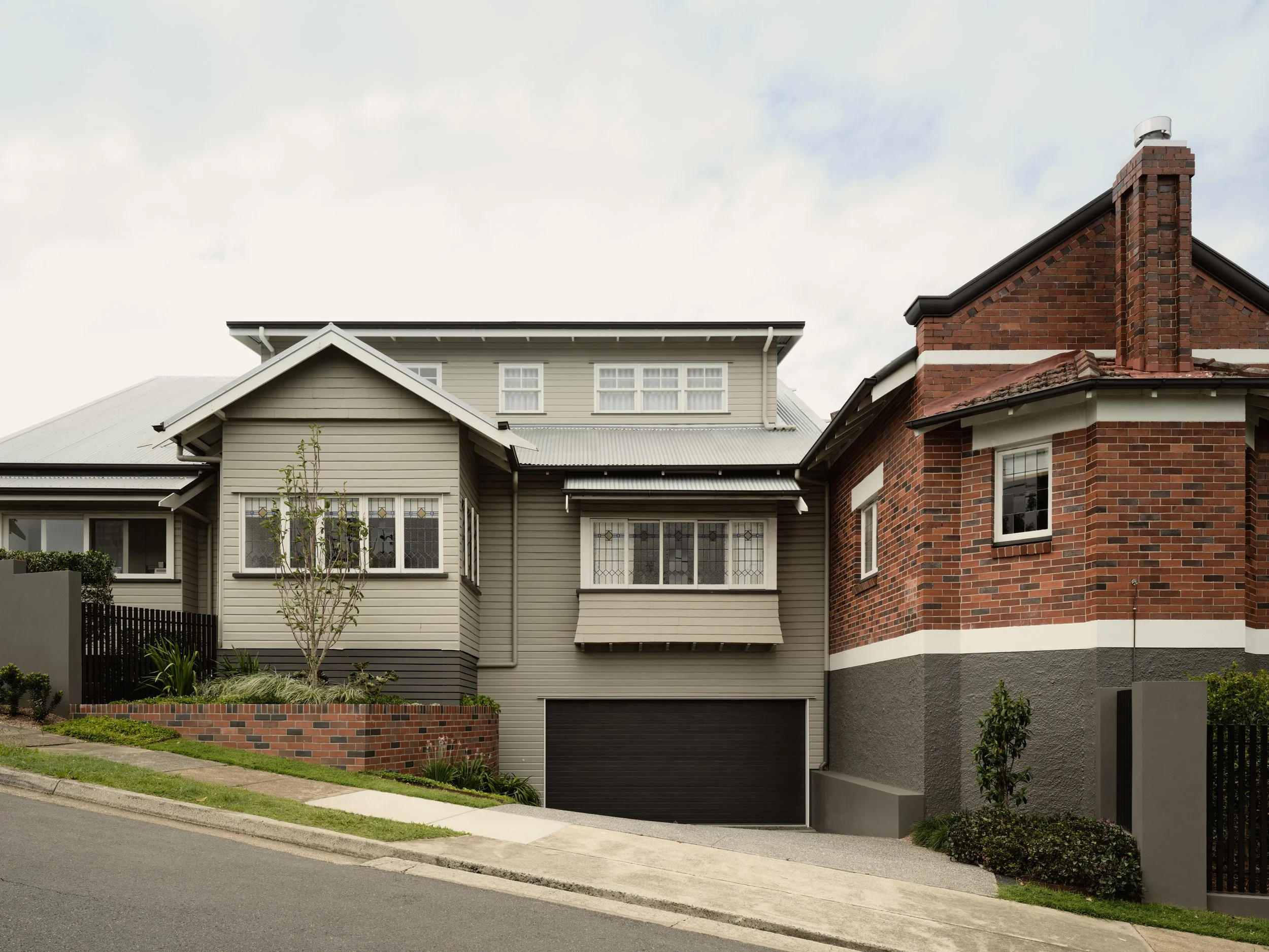 Heritage home on a sloping site with brick retaining wall, stained‑glass windows and landscaped front garden