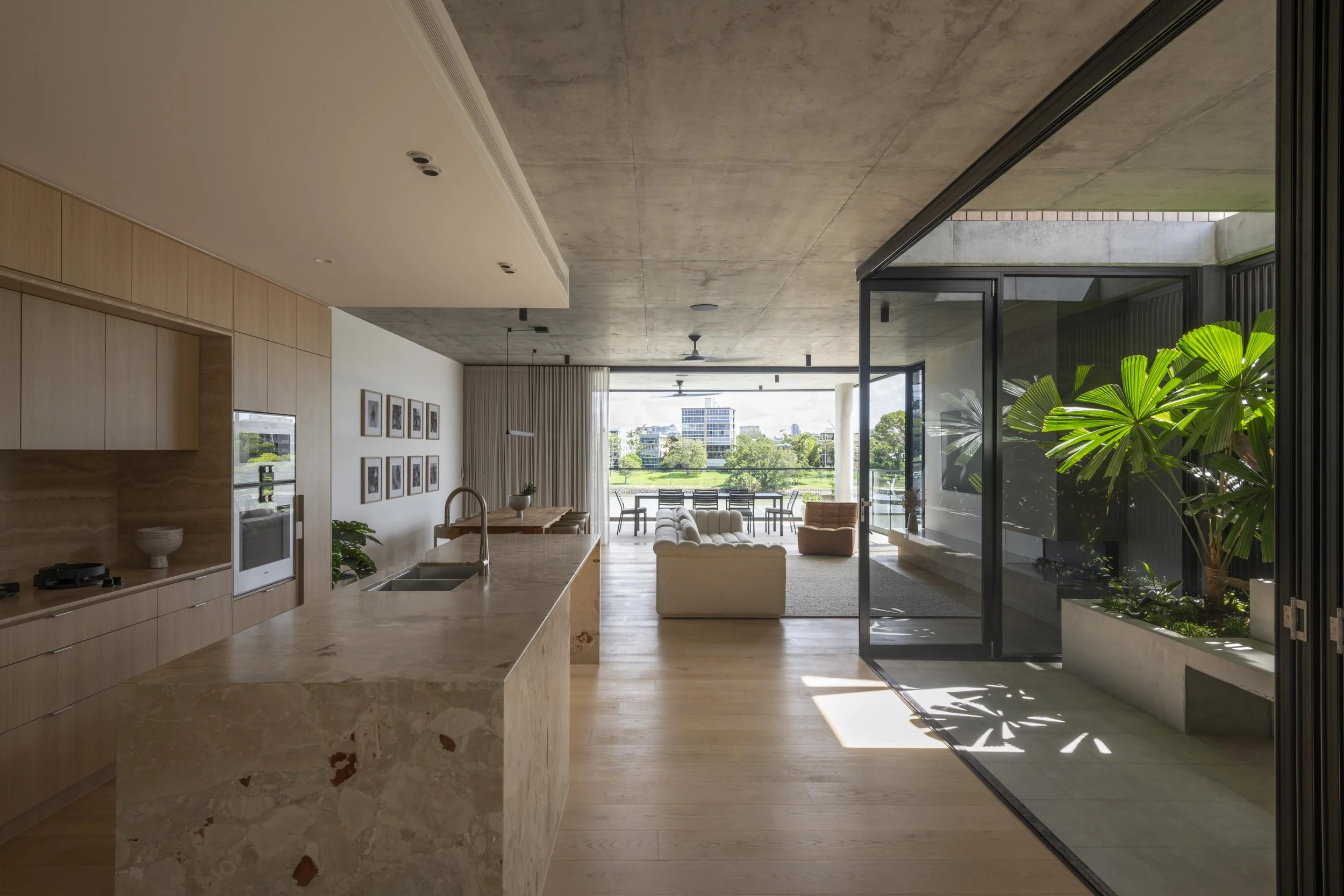 Open‑plan kitchen, dining, and living space with river views in a luxury Brisbane home by Allen Brothers Construction.