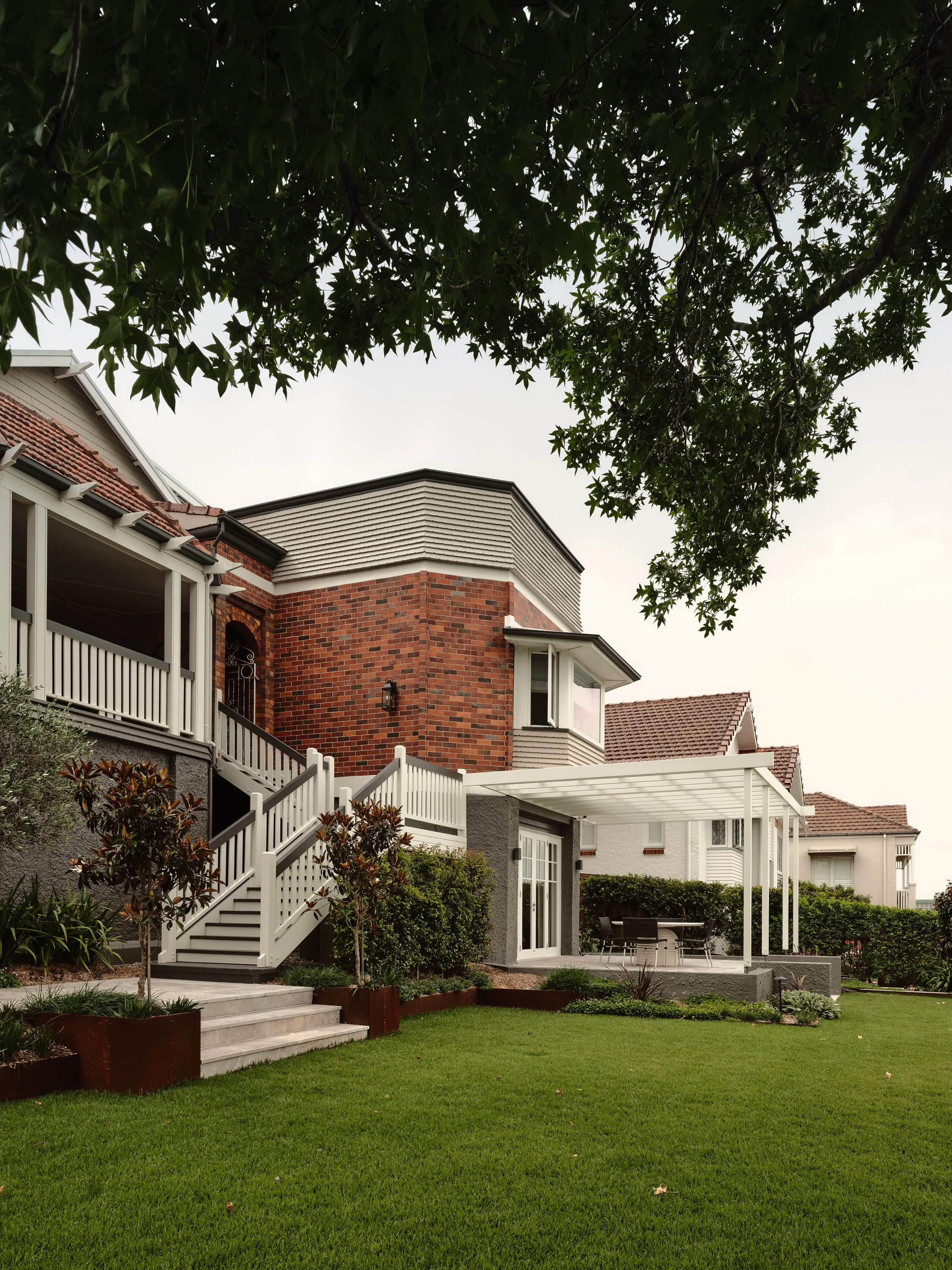 Renovated heritage home with modern pergola, landscaped gardens and elevated entry staircase