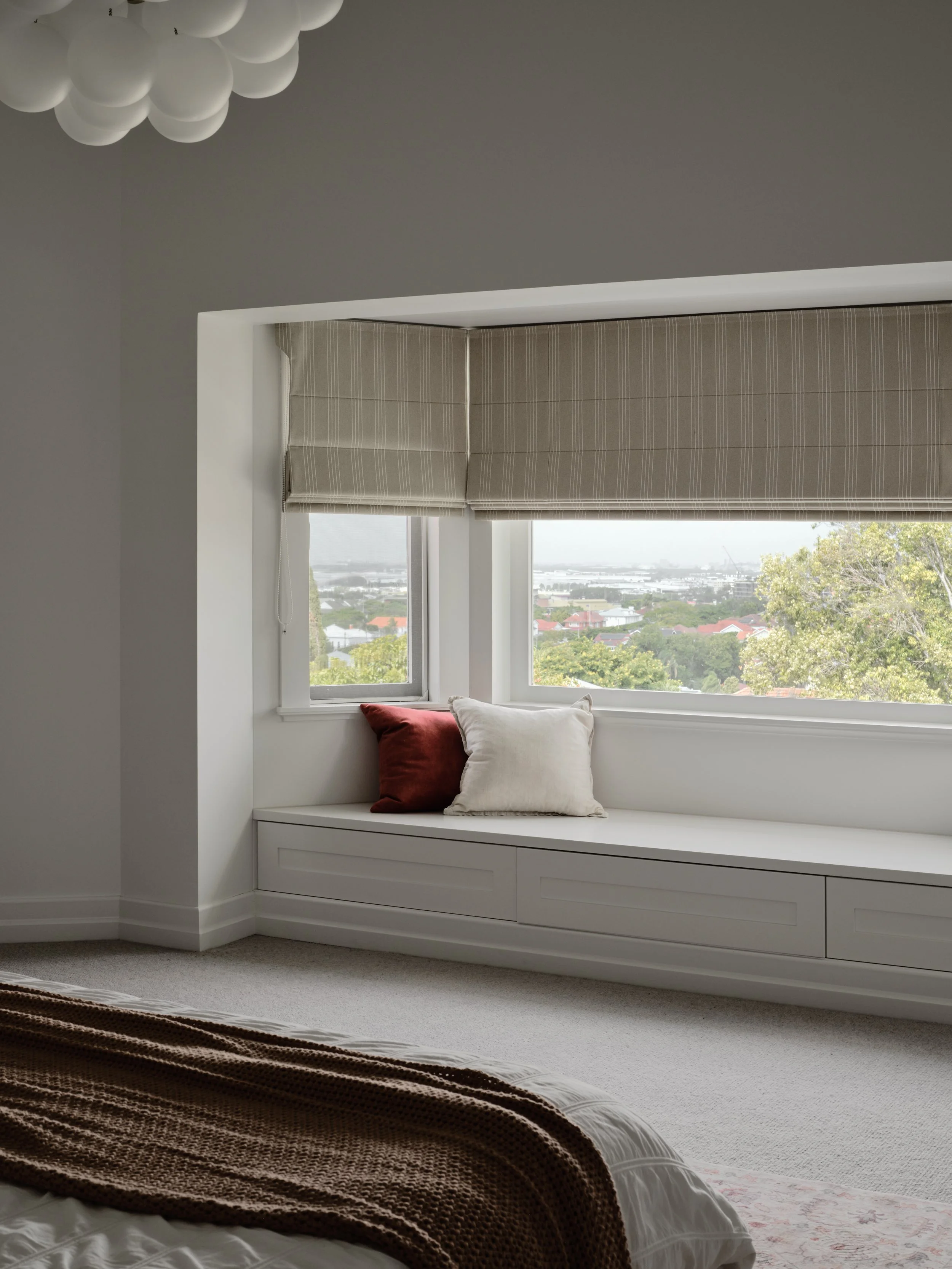 Bedroom window seat with storage, Roman shades and elevated suburban views in a luxury renovation