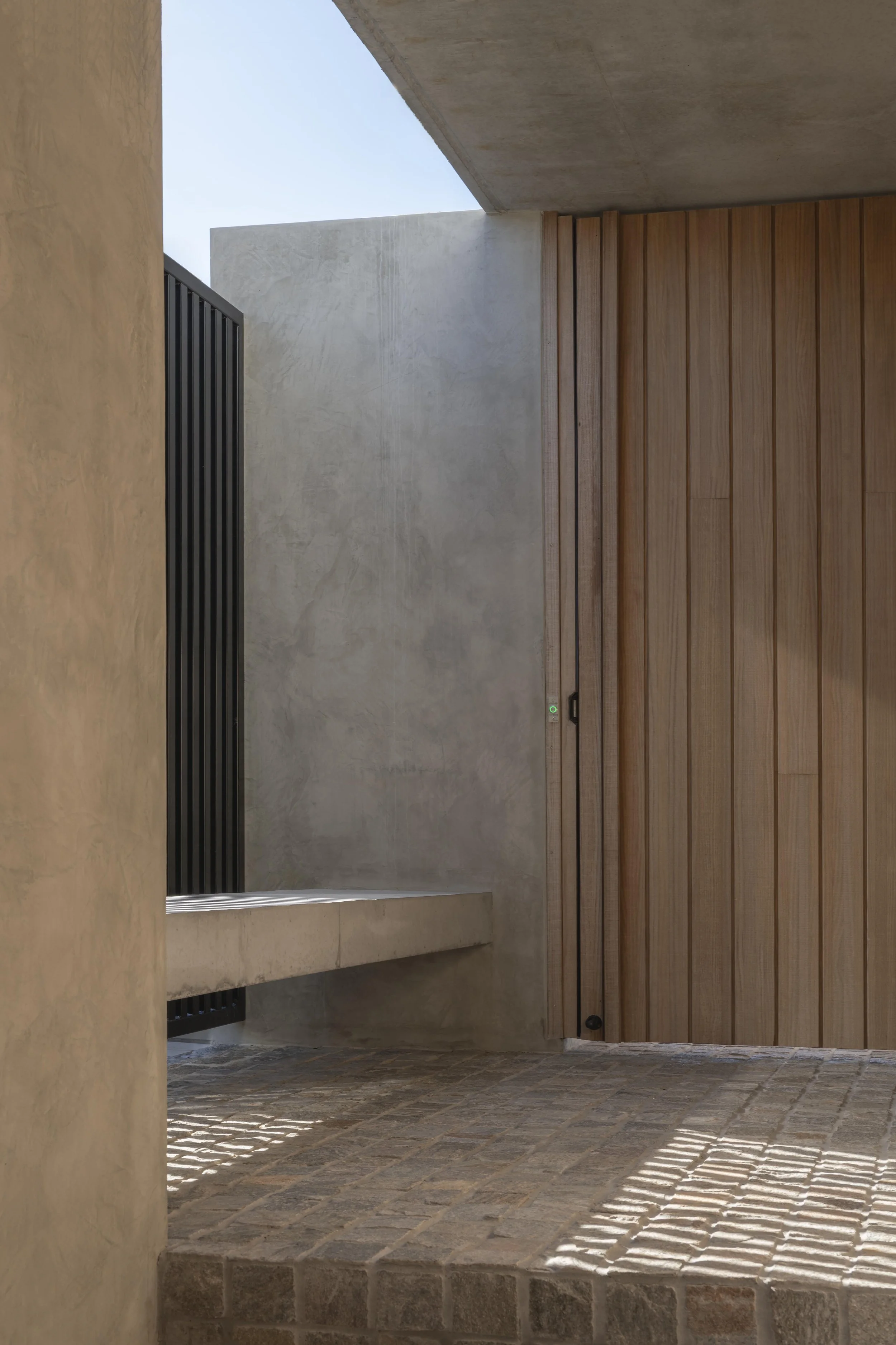 Minimalist concrete and timber entryway with stone paving in a luxury Brisbane architectural home.