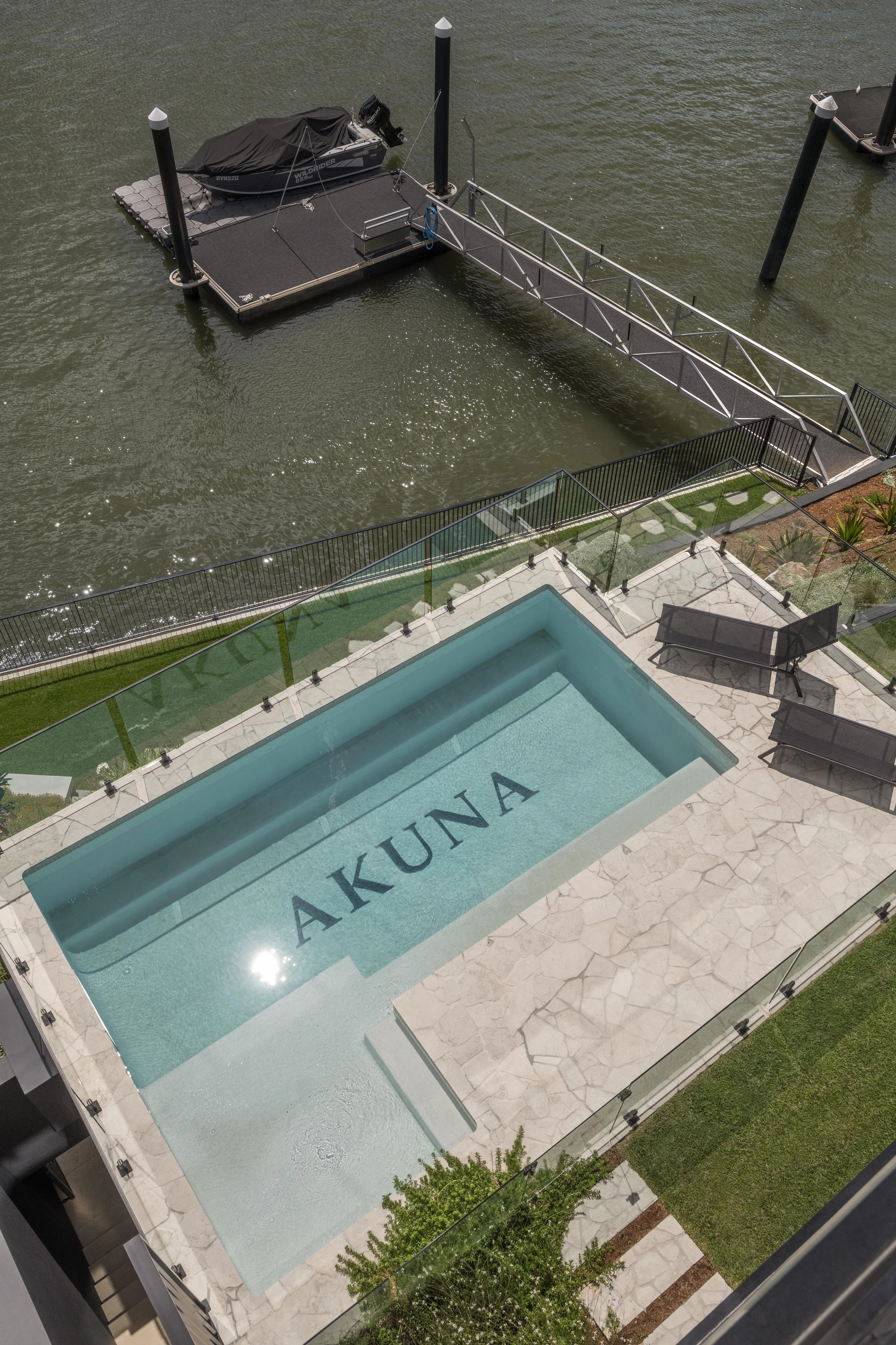 Riverfront pool, stone terrace, and private jetty at a luxury Brisbane home by Allen Brothers Construction.