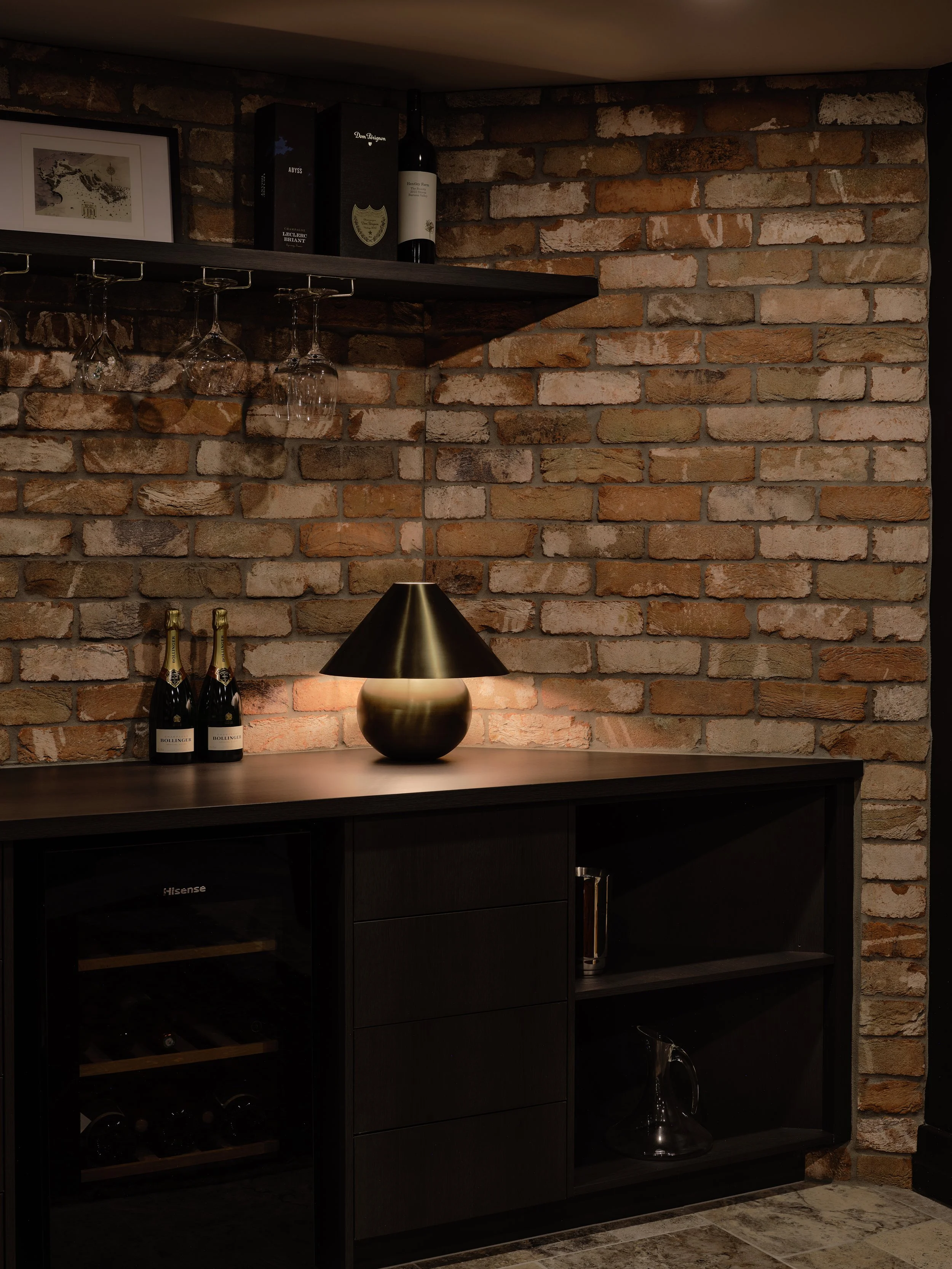 Wine room desk area with exposed brick, bar setup and integrated wine fridge