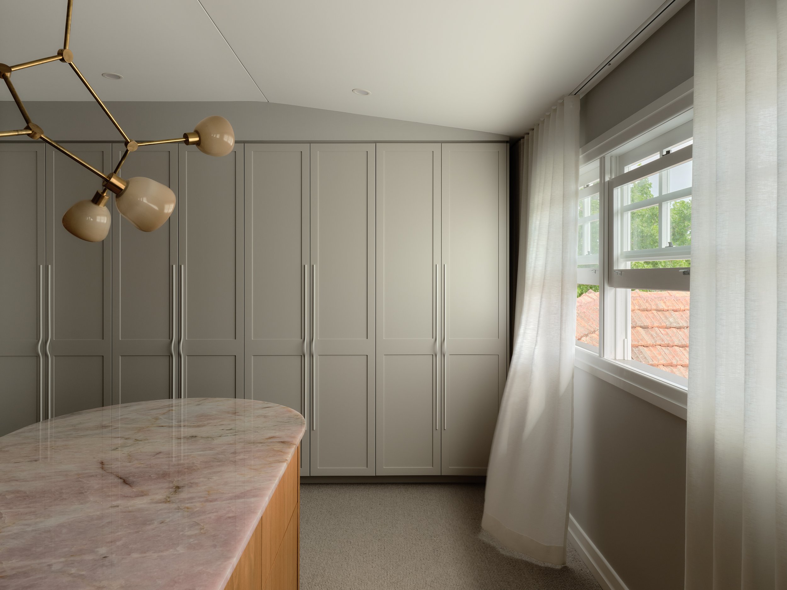 Her’ walk‑in robe with full‑height cabinetry, marble counter and brass feature lighting
