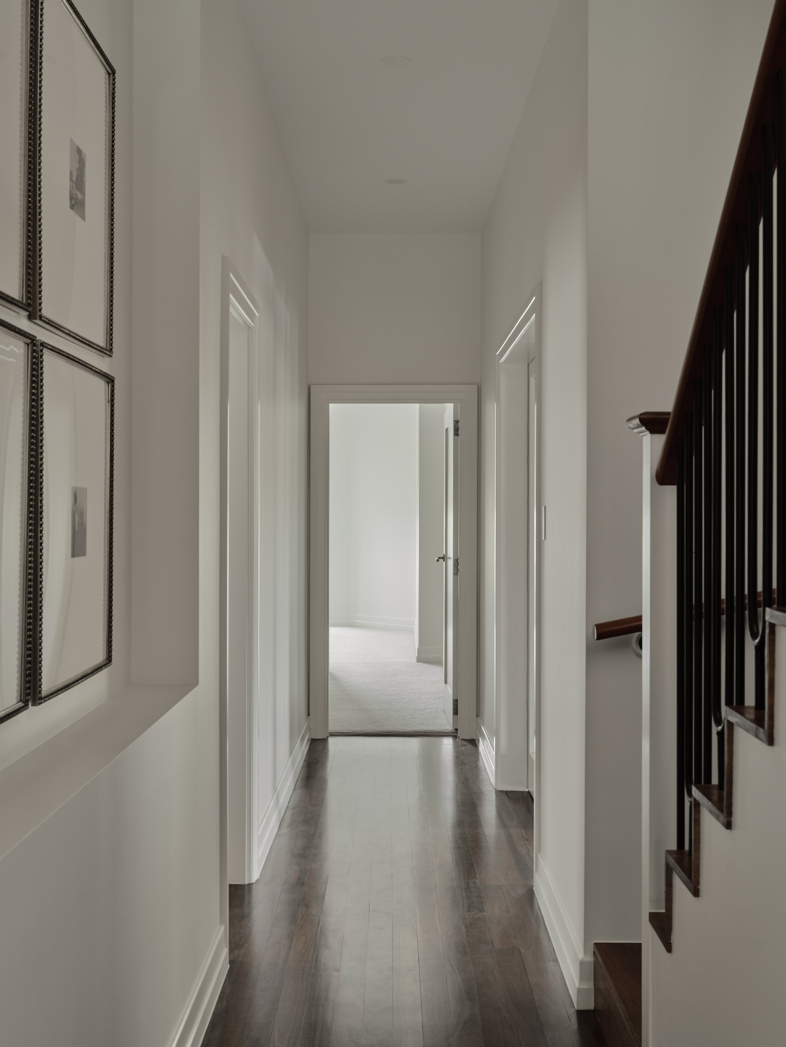 Modern hallway with dark timber floors, white walls and a contemporary staircase in a renovated heritage home