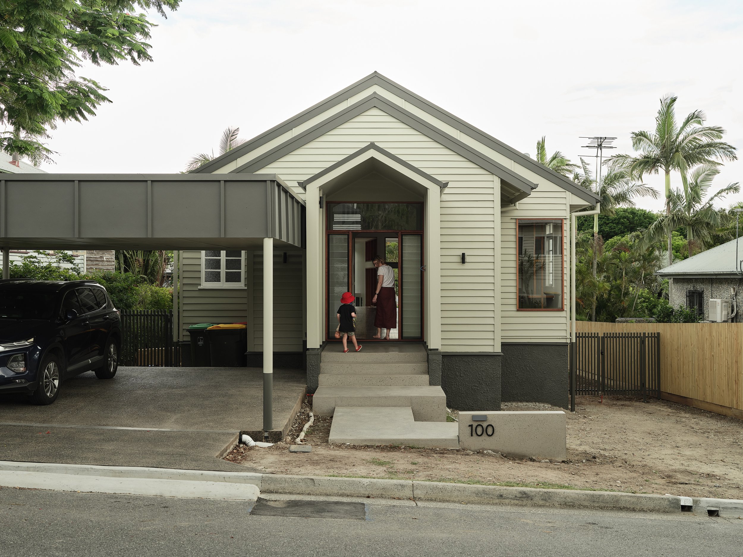 Client and her child at handover, standing at the front entry of their newly completed Brisbane home built by Allen Brothers Construction.