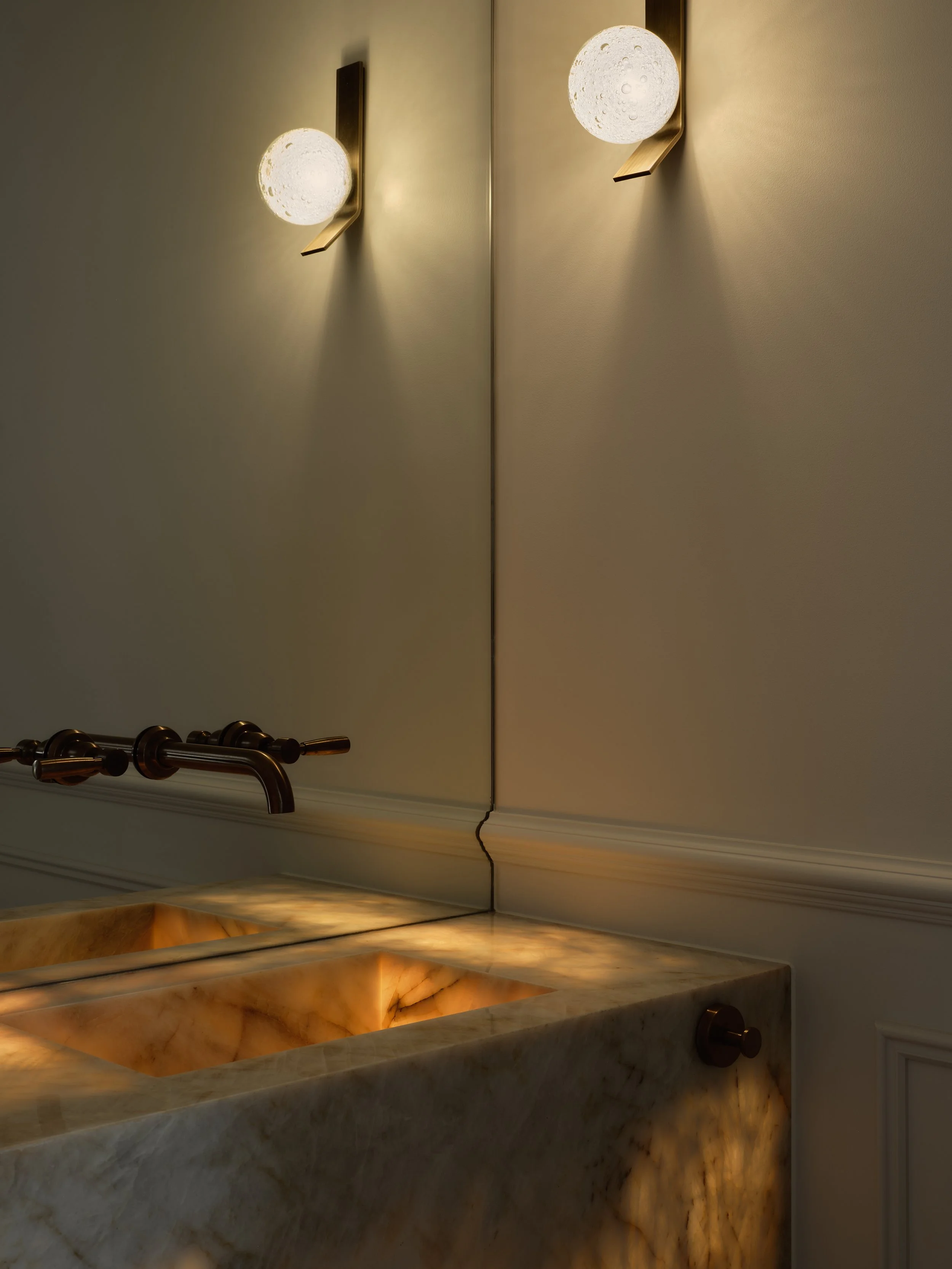 Luxury bathroom vanity with illuminated marble basin, wall‑mounted tapware and modern glass sconces