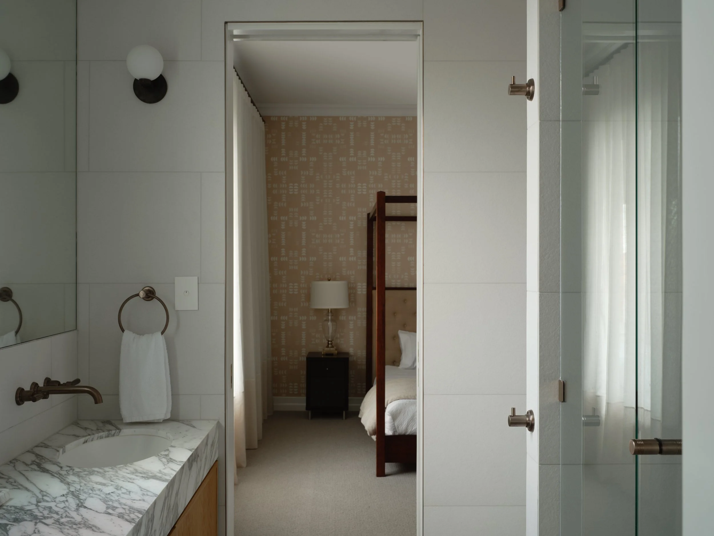 Modern bathroom with marble vanity opening into a luxury bedroom with four‑poster bed