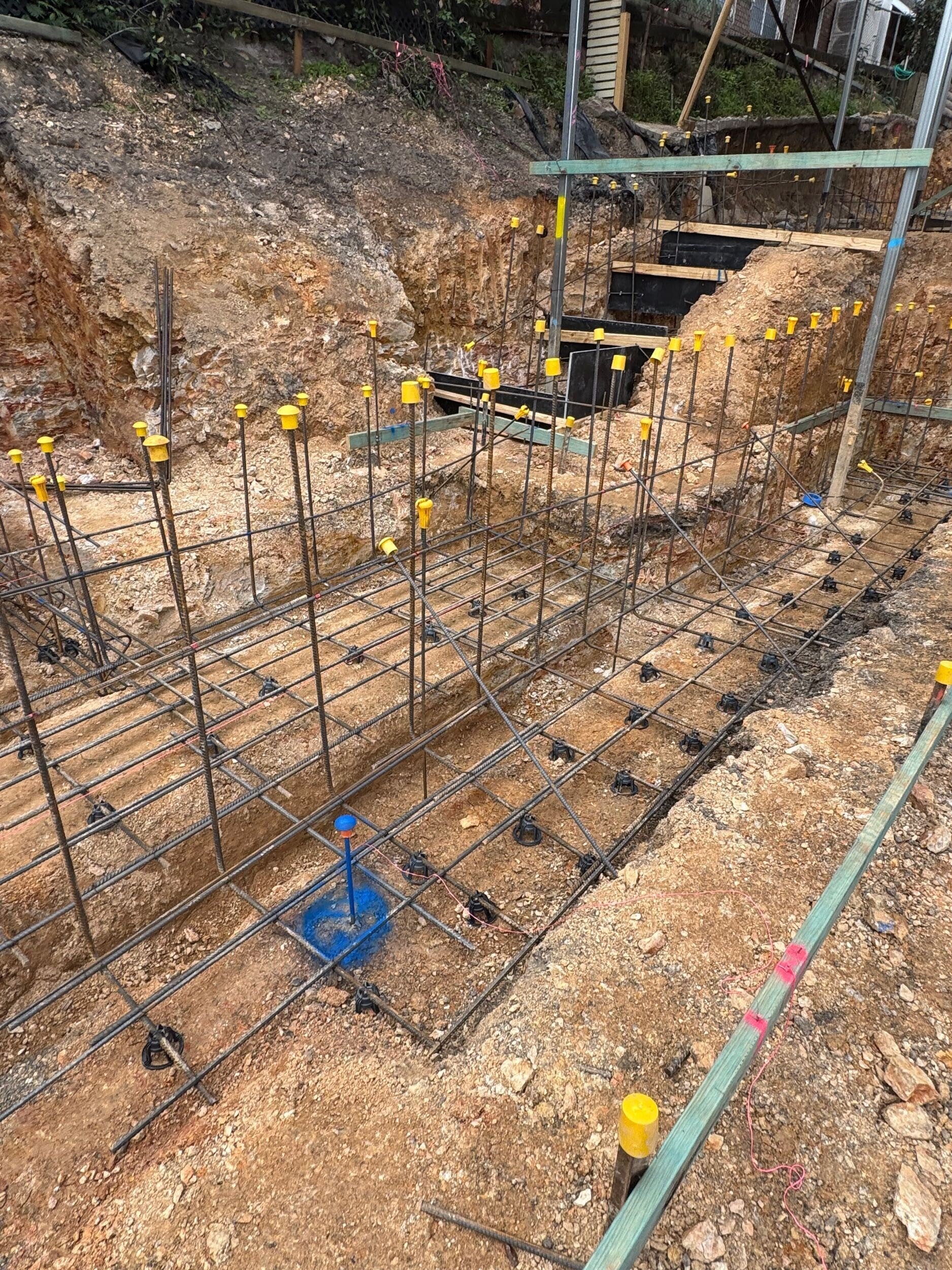 Reinforcement steel and footing trenches prepared for retaining wall construction at Project 136 Bulimba house raise and build‑under.