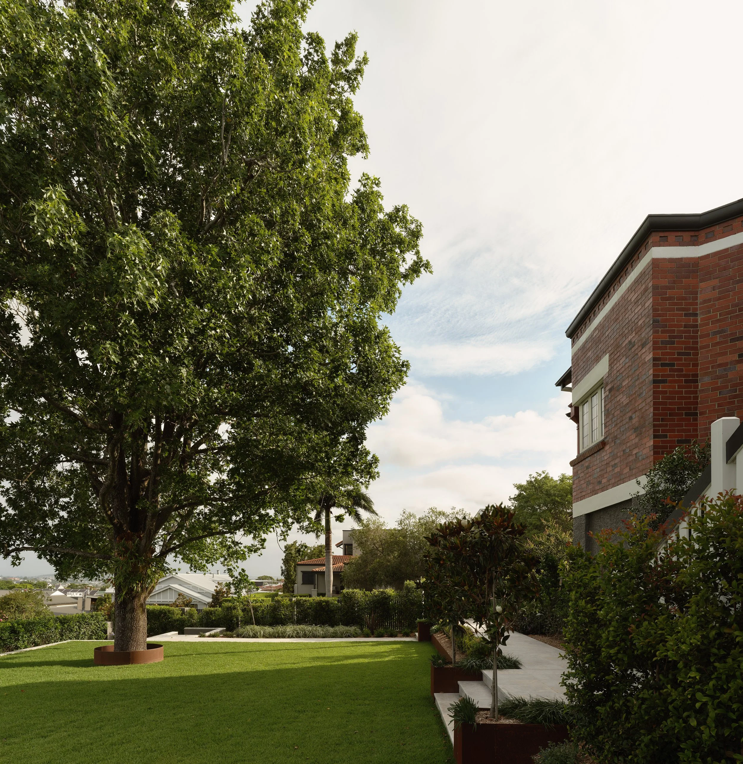 Side garden with manicured lawn, raised planting beds and heritage brick facade