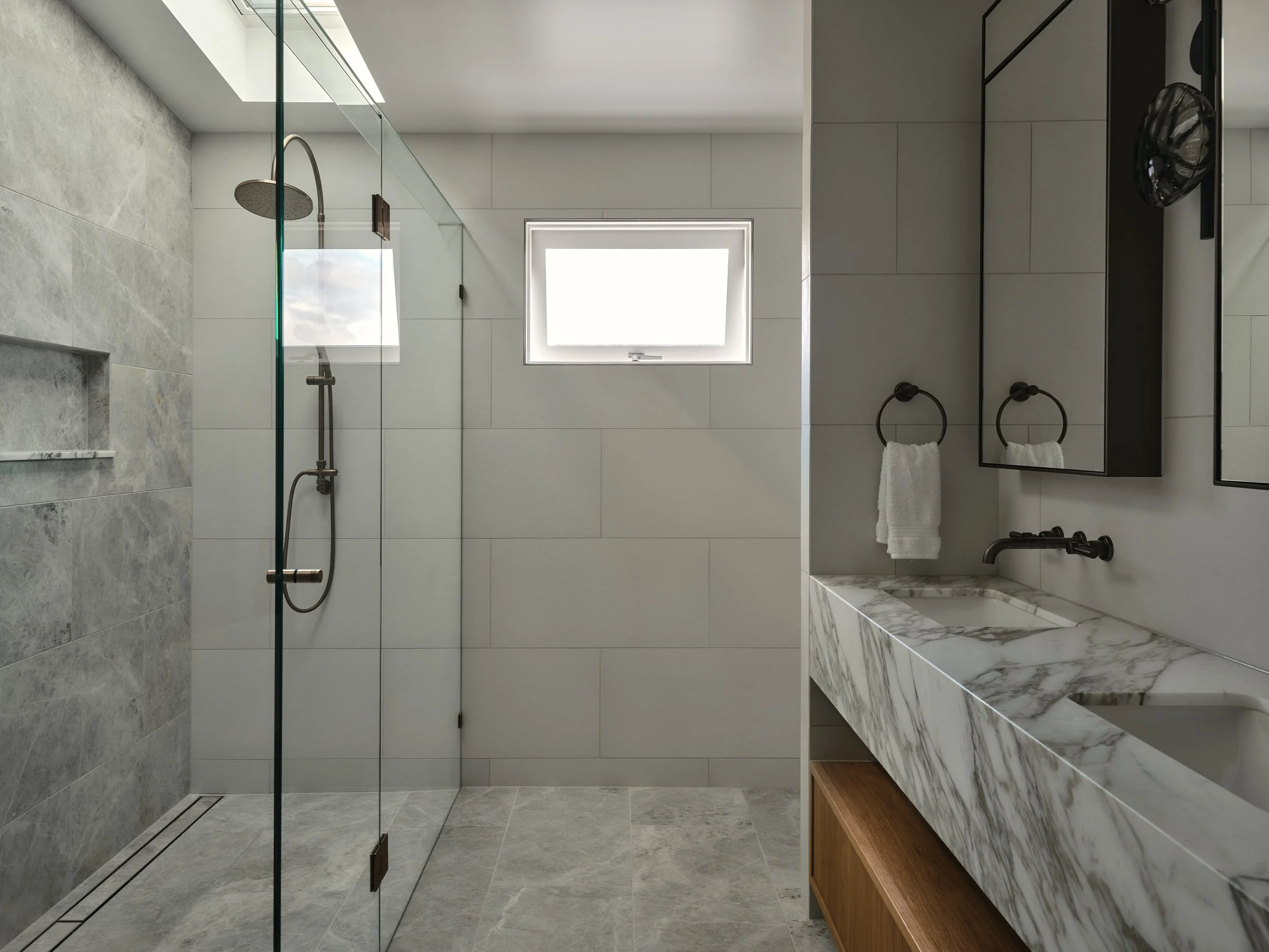 Luxury bathroom with marble walk‑in shower, double vanity and brodware statue bronze fixtures