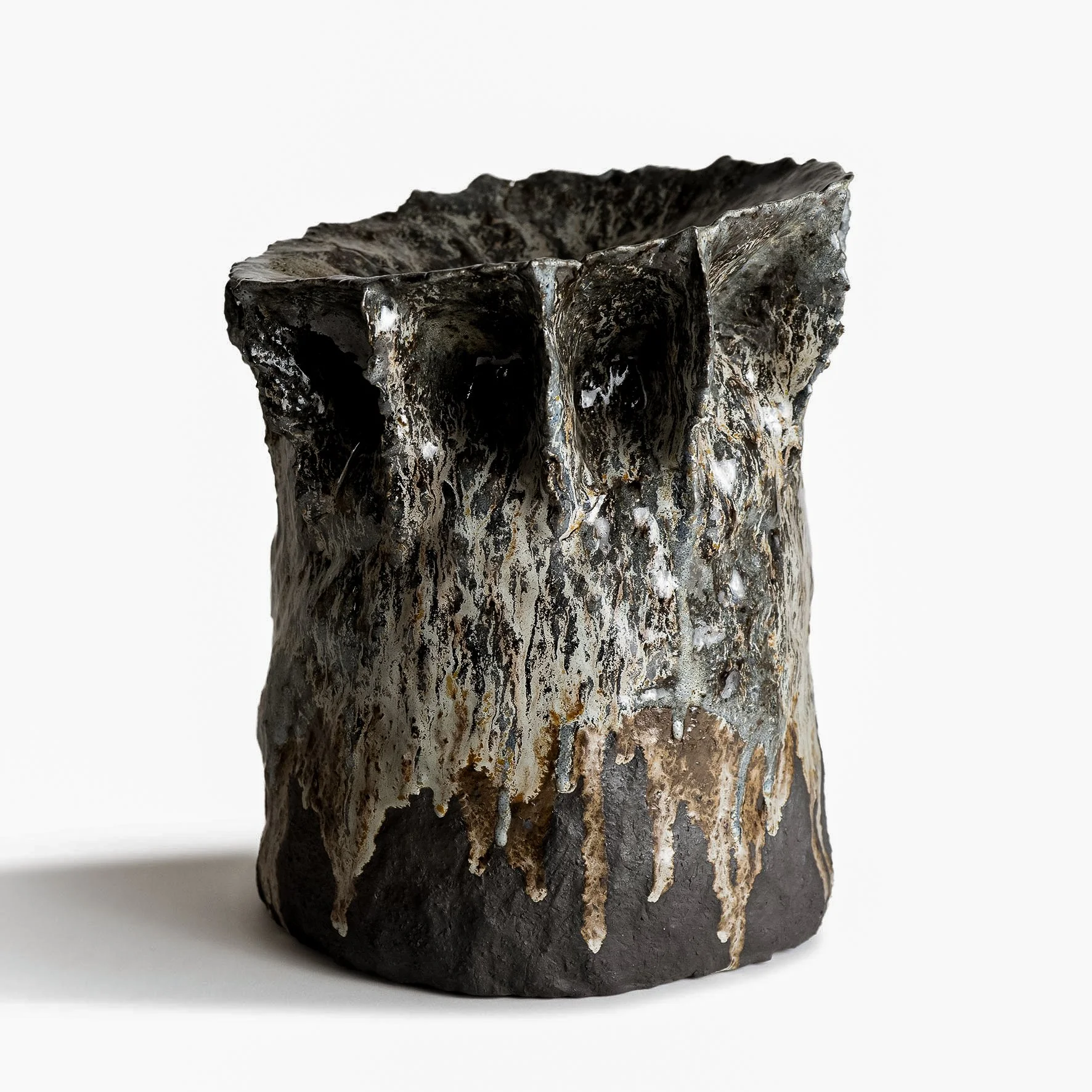 Abstract ceramic vase with dark, textured surface and metallic accents, set against a plain white background.