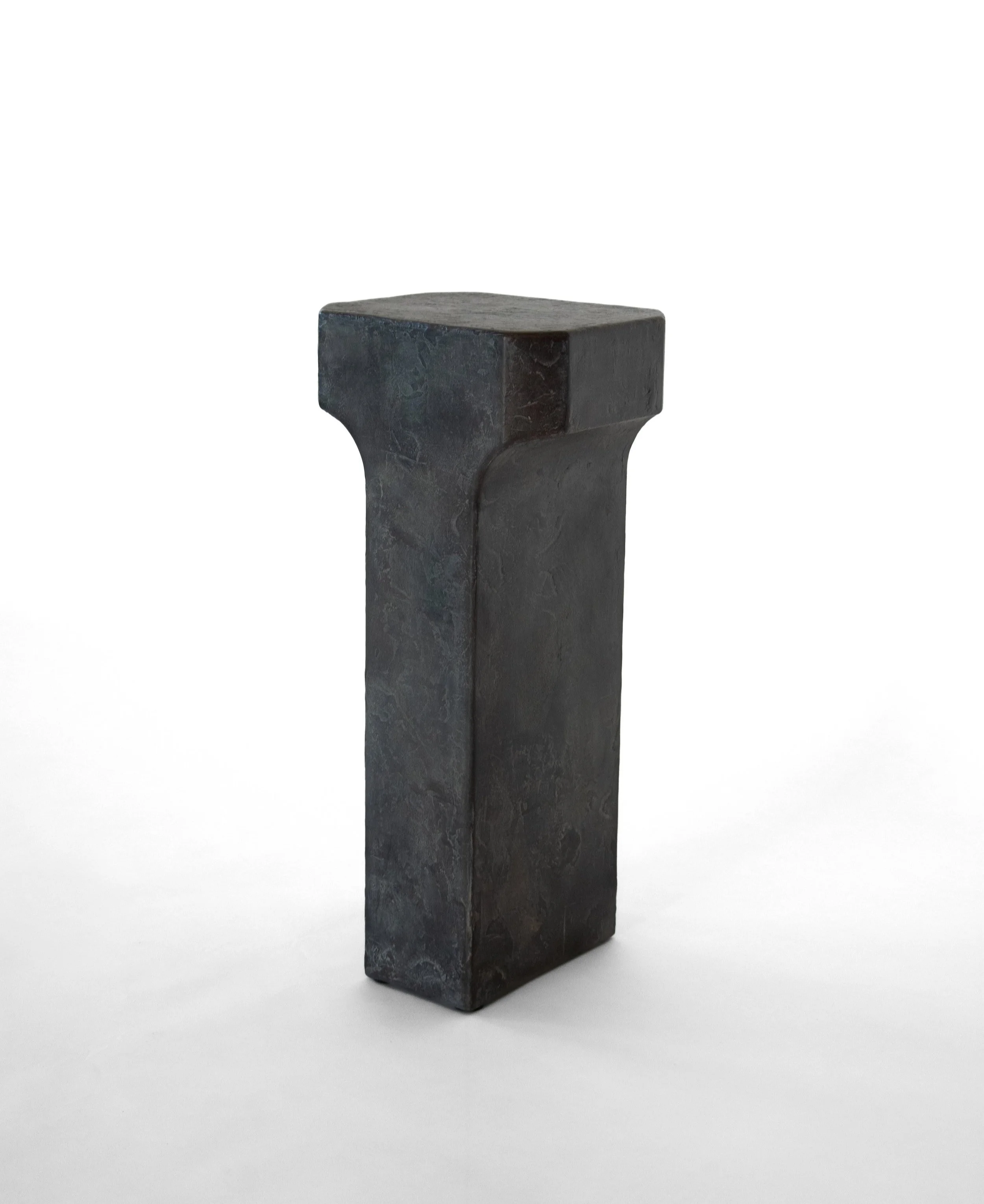 A black, rectangular bronze sculpture with rounded edges, standing upright against a plain white background.