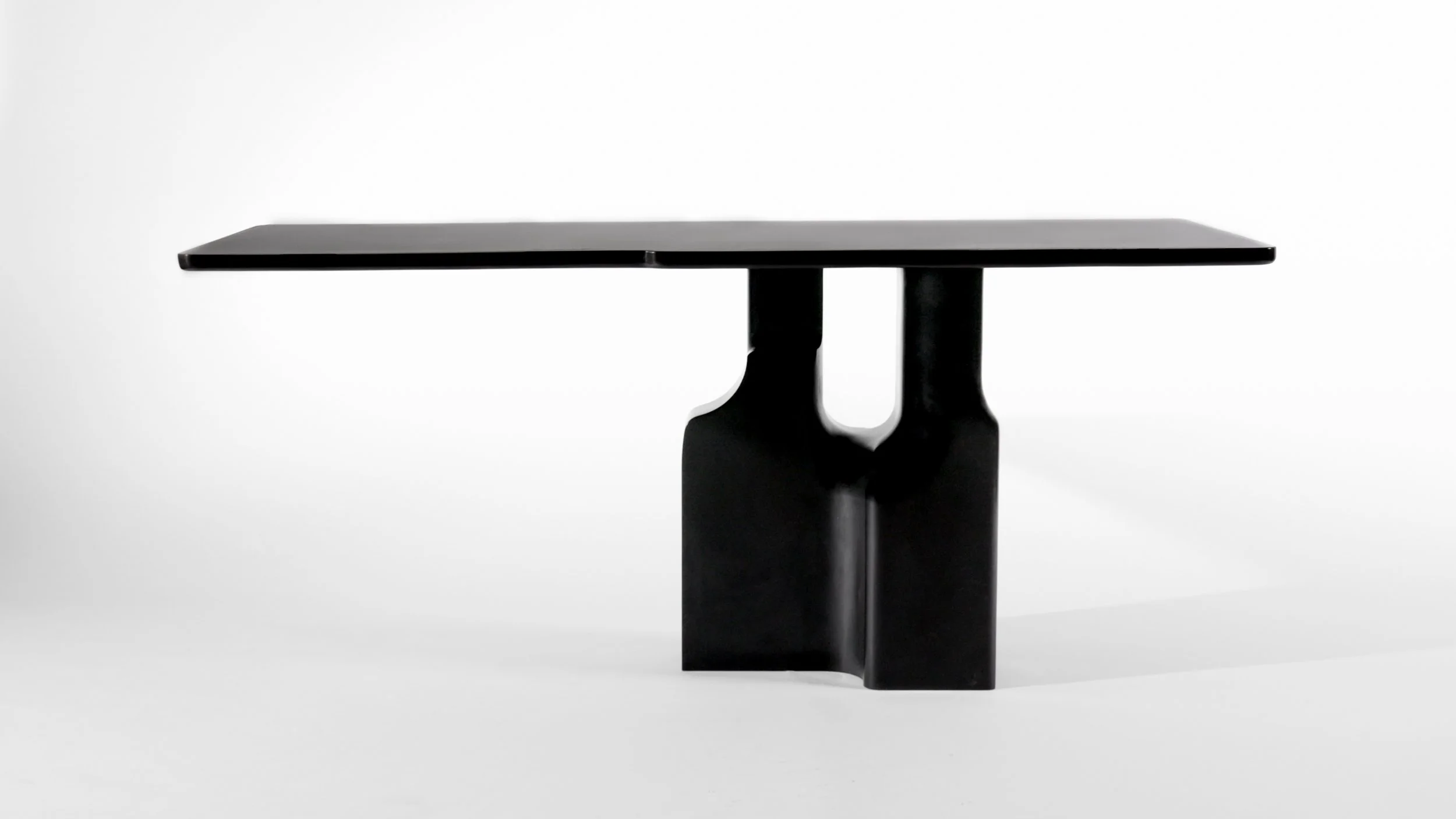 Black bronze table with a minimalist design and sculptural base, set against a plain white background.