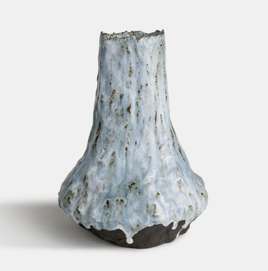 ceramic vase with a textured, drip-glazed finish in shades of blue and white, with a dark base, on a plain background