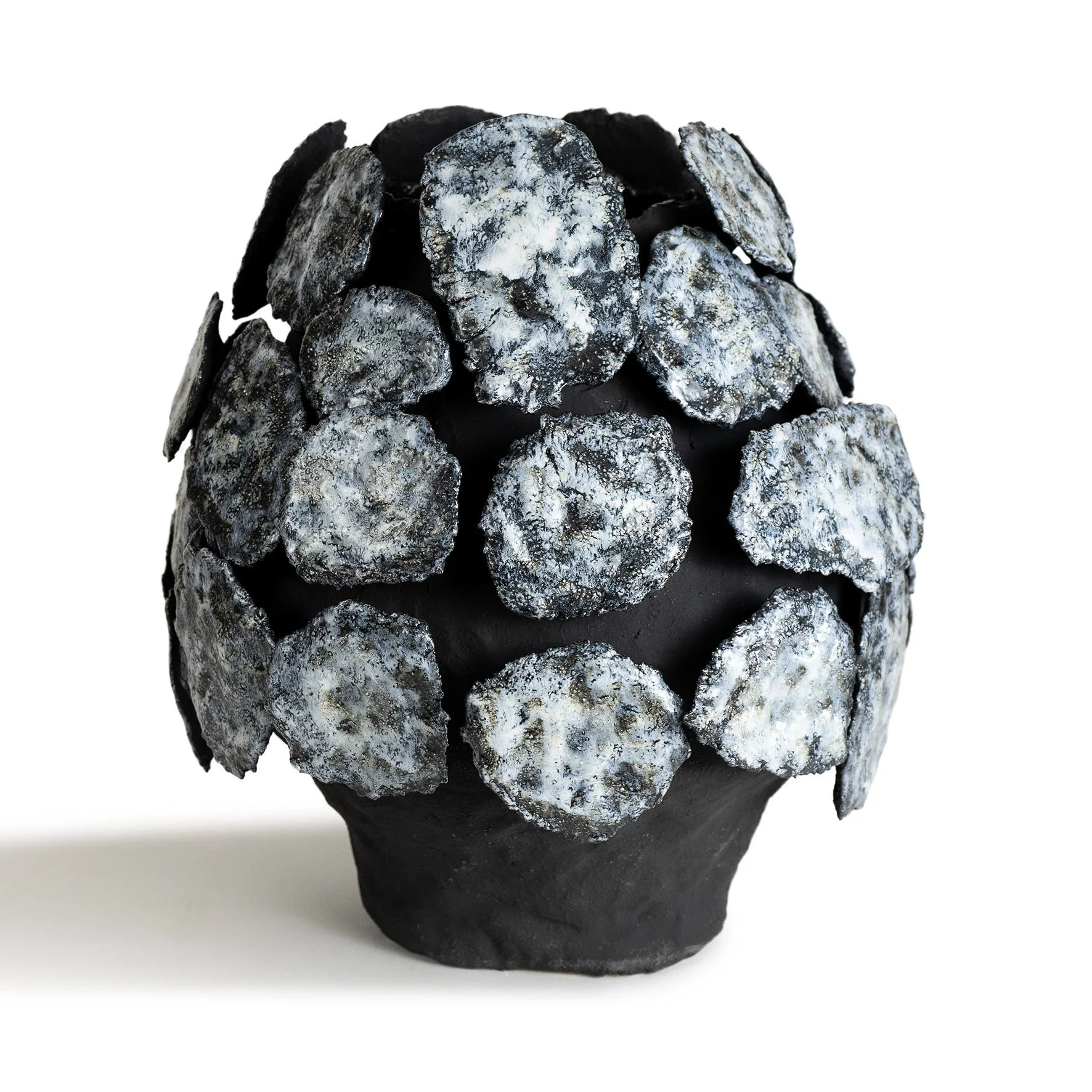 Black ceramic bowl filled with irregularly shaped black and white crystalline stones or minerals.