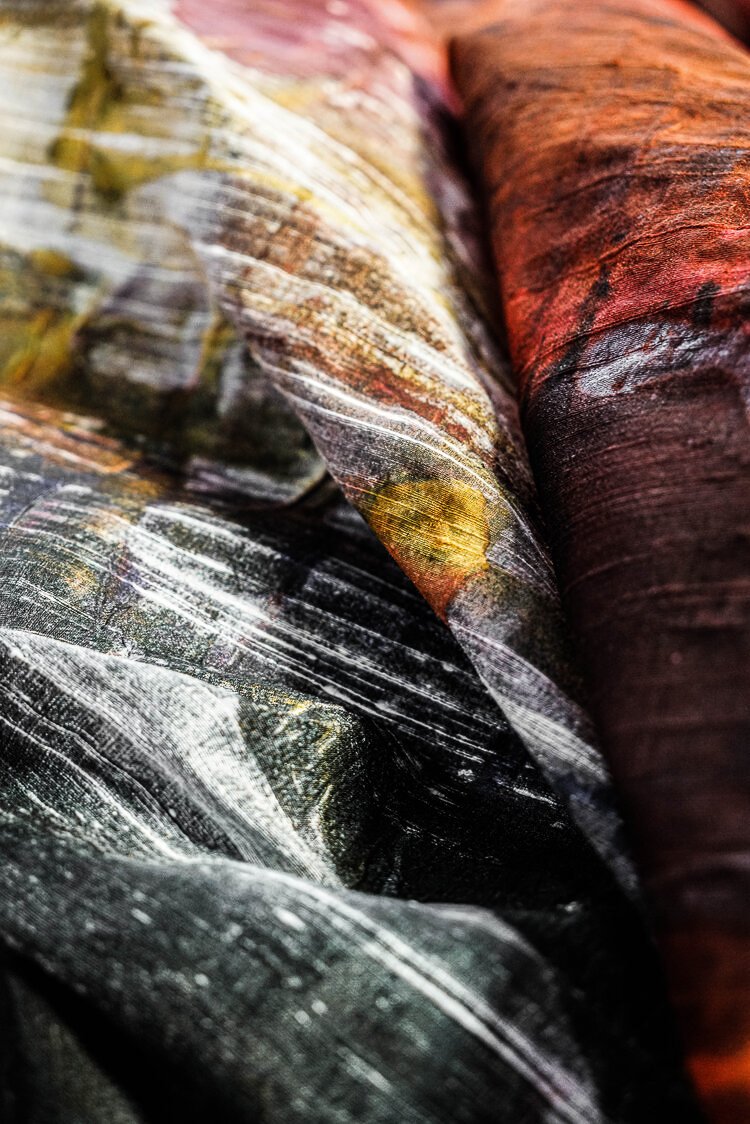 Close-up of layered, textured fabric with colorful patterns, including shades of black, yellow, green, and red.
