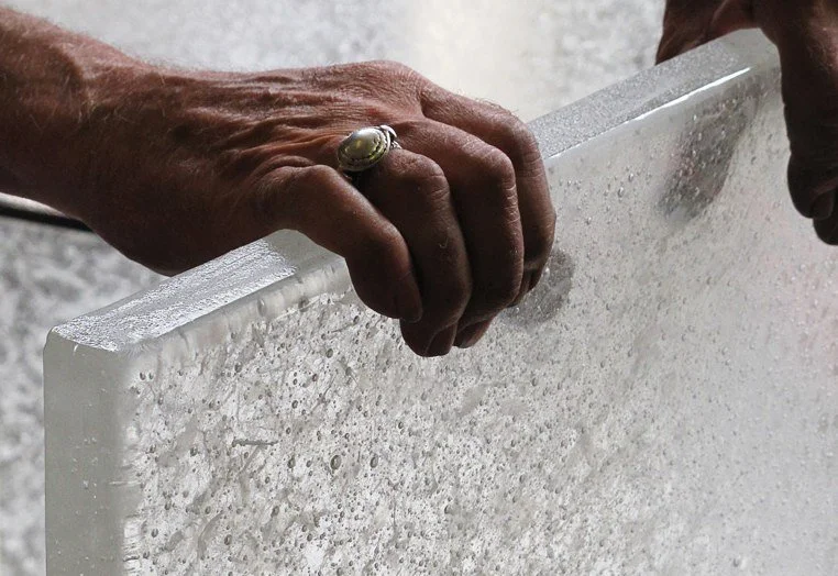 Two hands holding a large rectangular sheet of textured glass