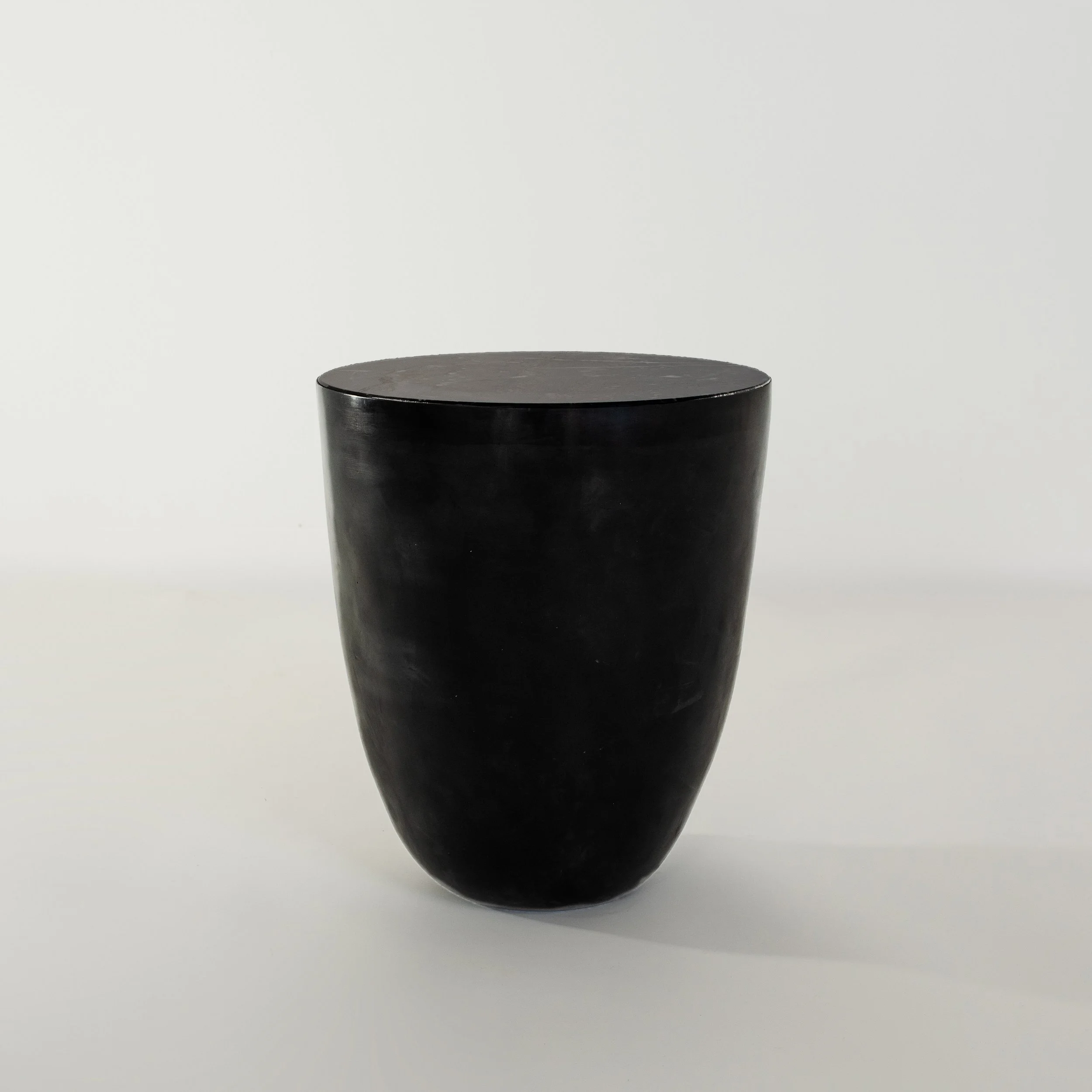 A black, glossy, rounded cylindrical object with a flat top, set against a plain white background.