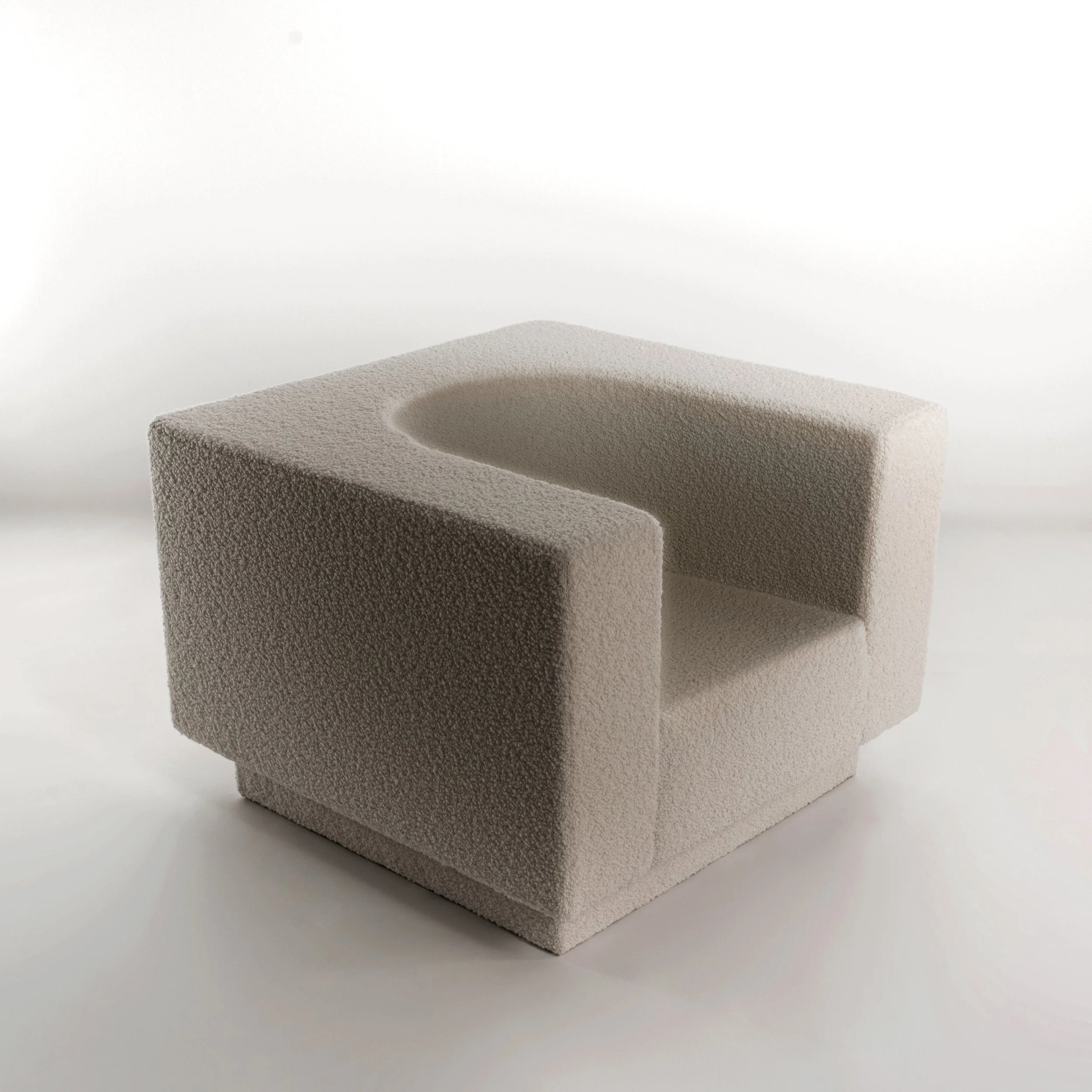 Modern beige armchair with a geometric design and textured fabric upholstery.
